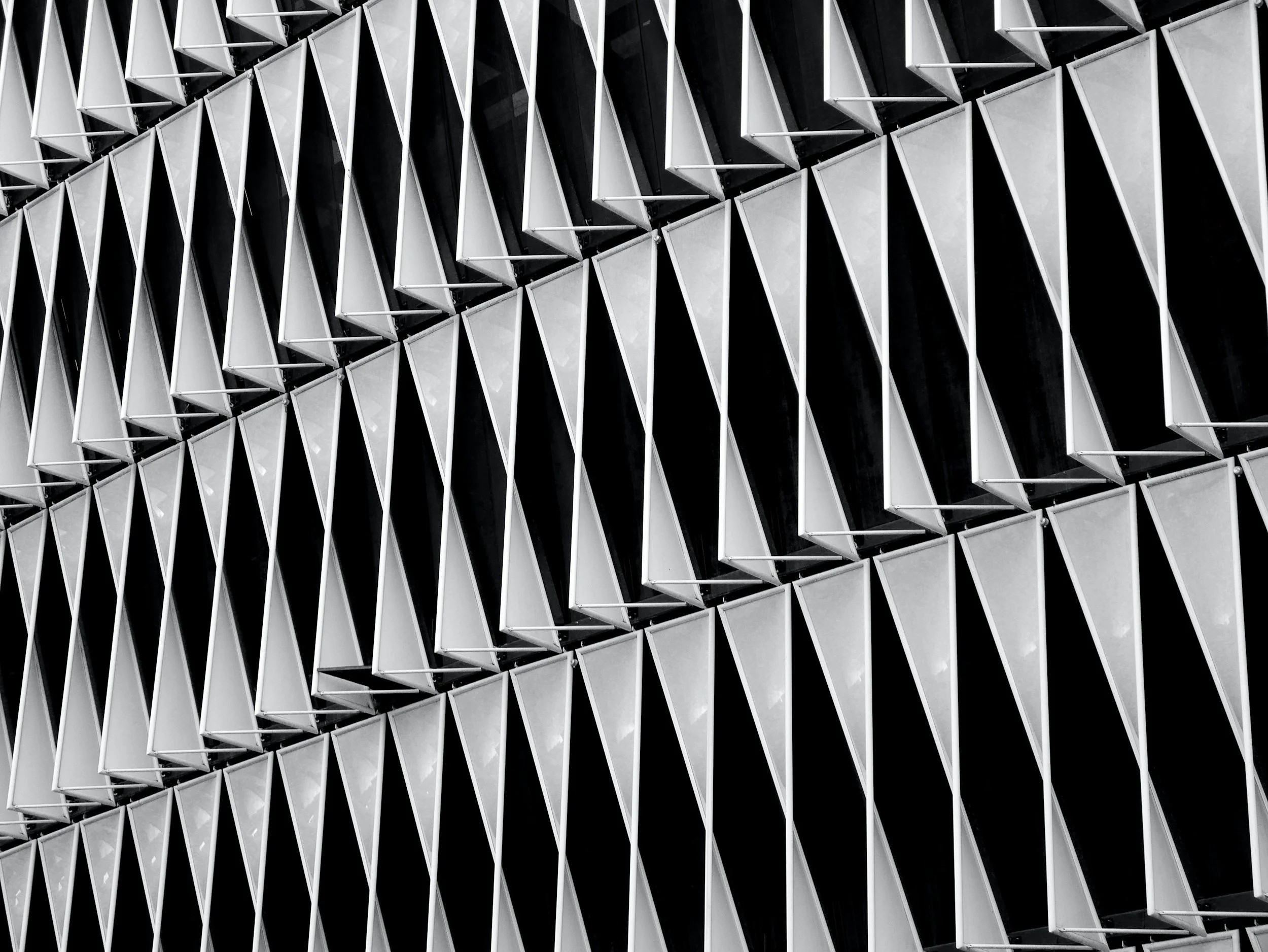 Close-up of a modern building facade featuring geometric patterns with a repeating diamond-shaped design in black and white.