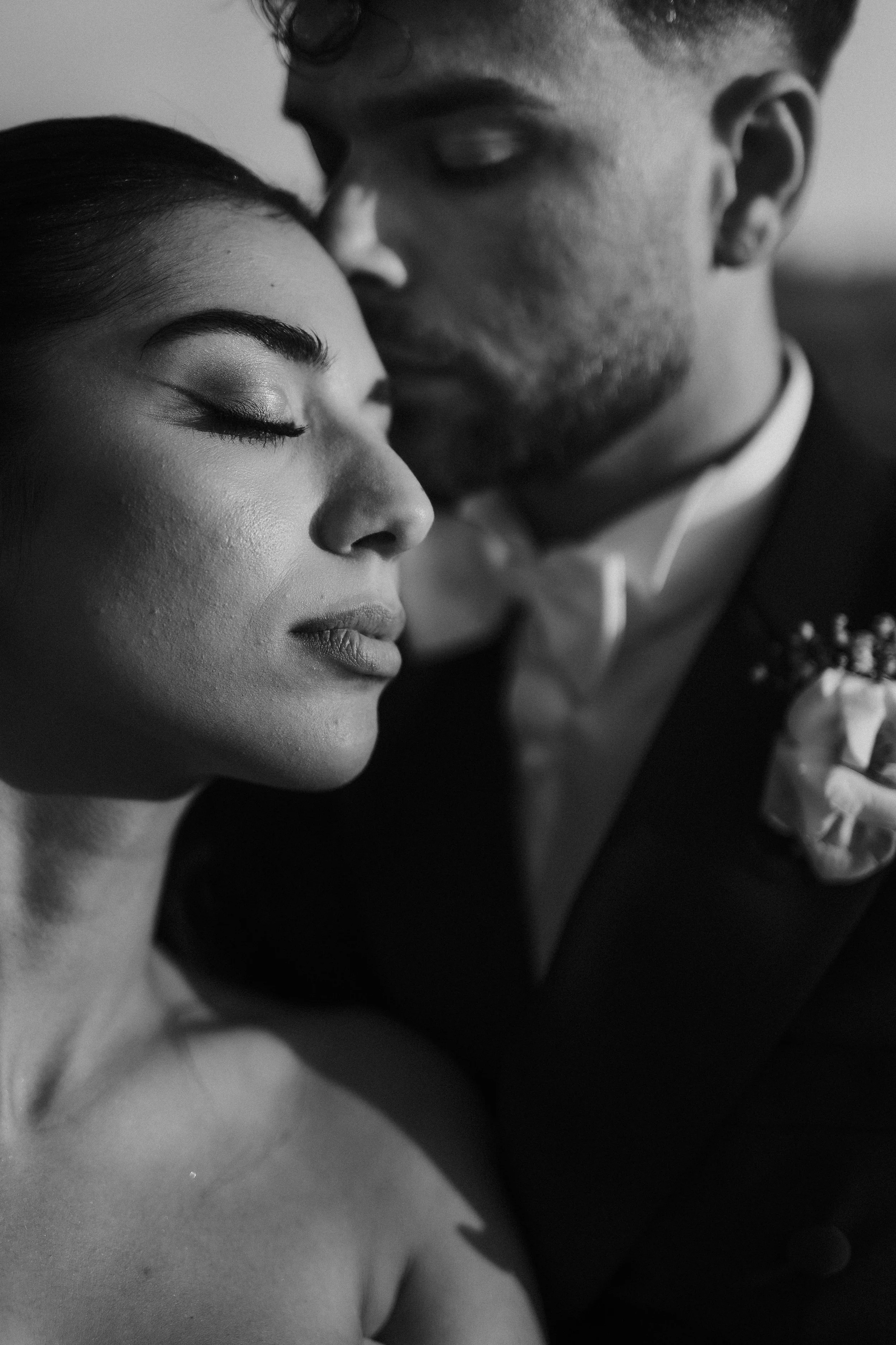 Una coppia di persone che si abbracciano molto vicino, con la donna con gli occhi chiusi e il uomo che si avvicina al suo viso in un gesto intimo.