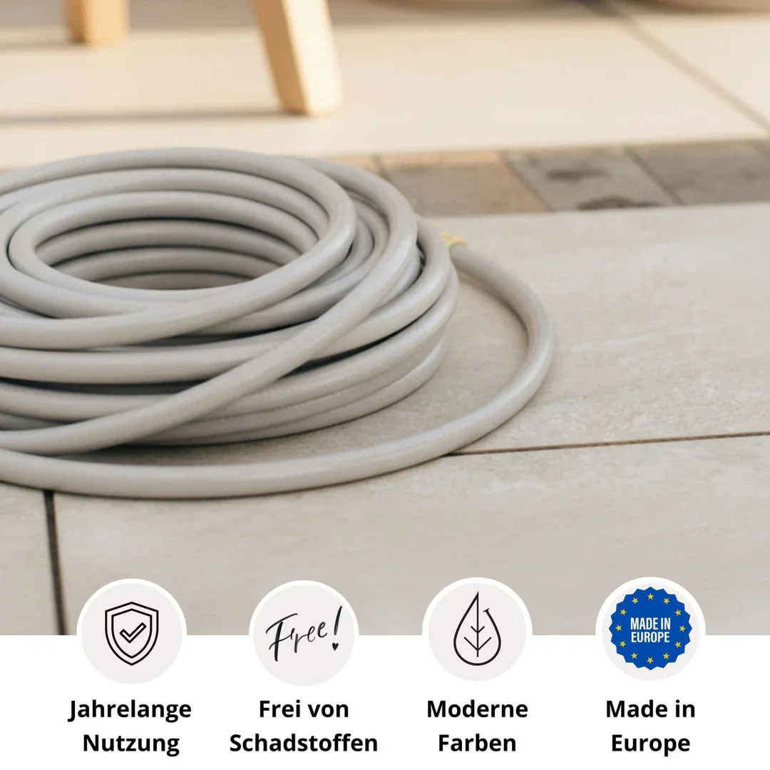 A coiled grey electrical cable on a tiled floor with a chair leg visible in the background.