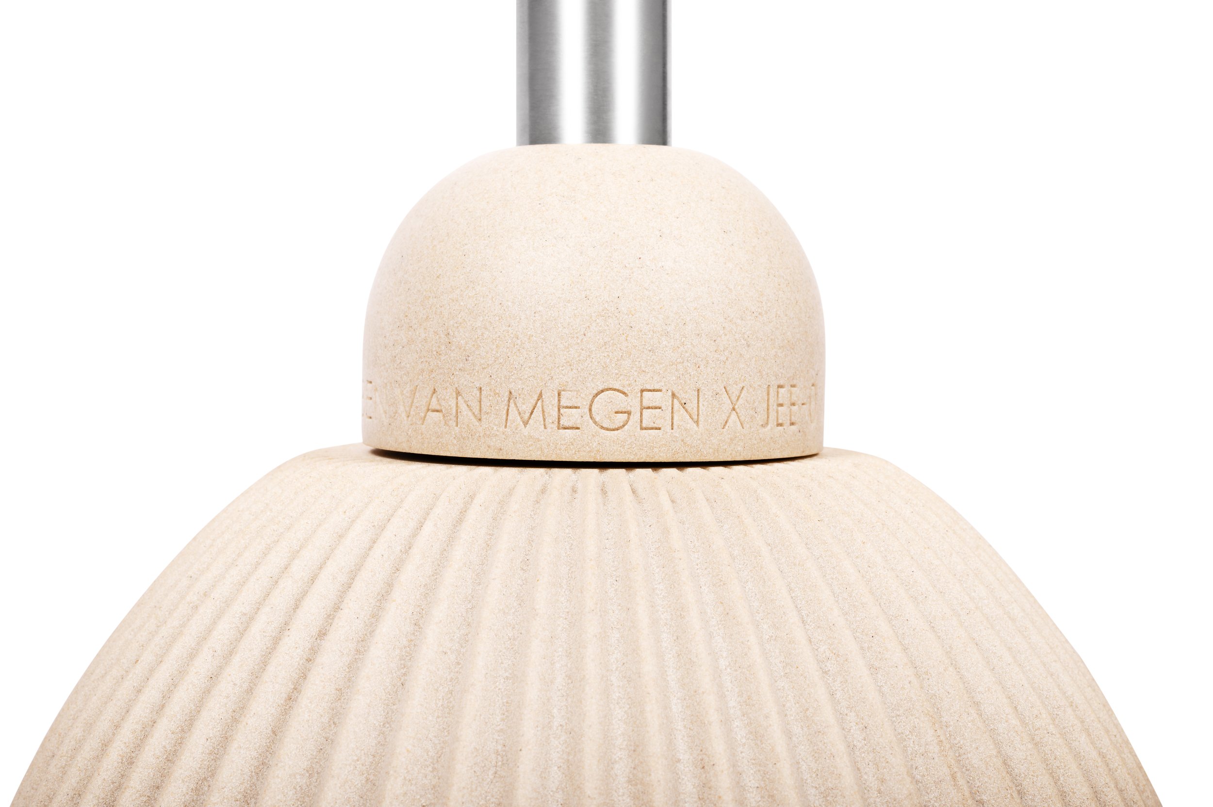 Close-up of a wooden object with engraved text 'VAN MEGEN X JEE' and a metallic attachment at the top, against a white background.
