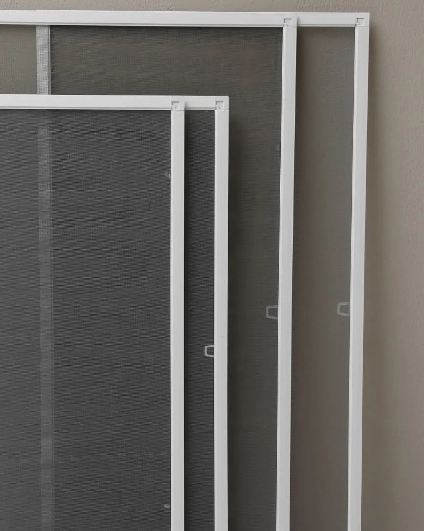 Three white window screens leaning against a gray wall.
