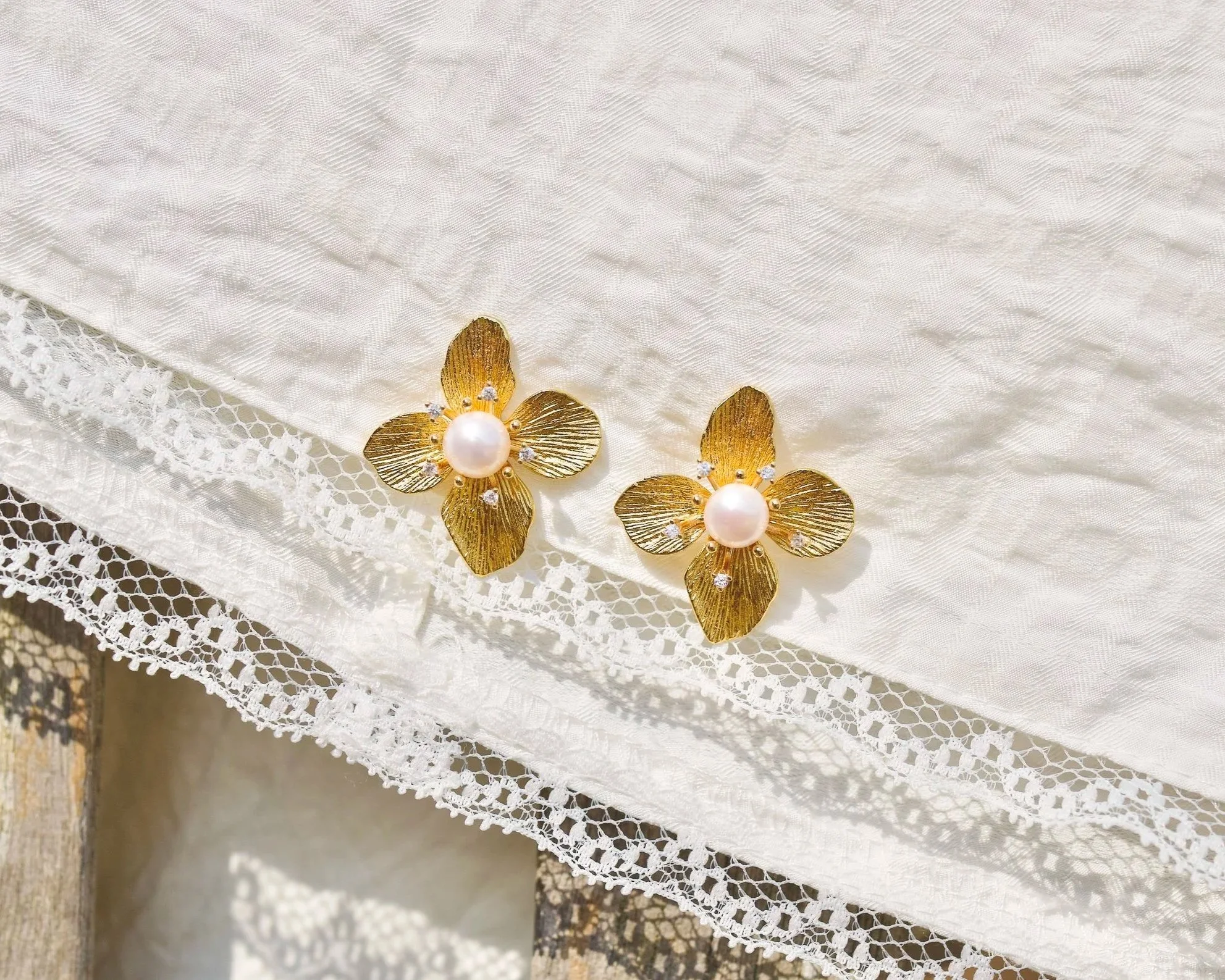 gold plated flower-shaped earrings featuring pearl centers and top grade cubic zirconia.