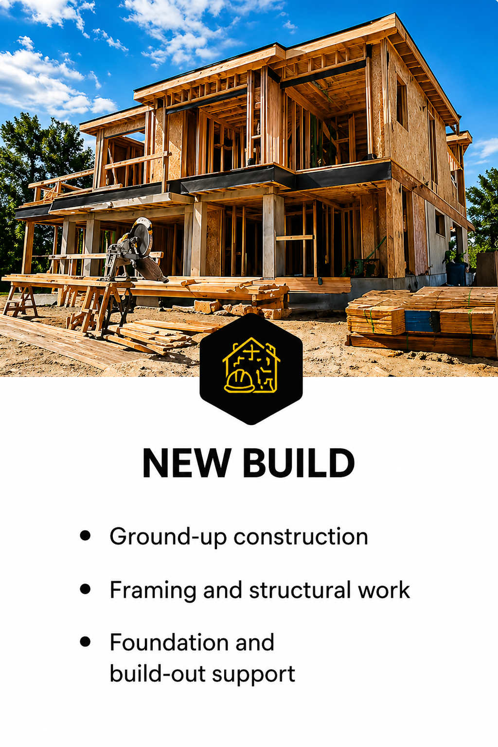 A house under construction made of wood, with framing and structural work visible. Construction materials and tools are present in the foreground. The sky is partly cloudy.