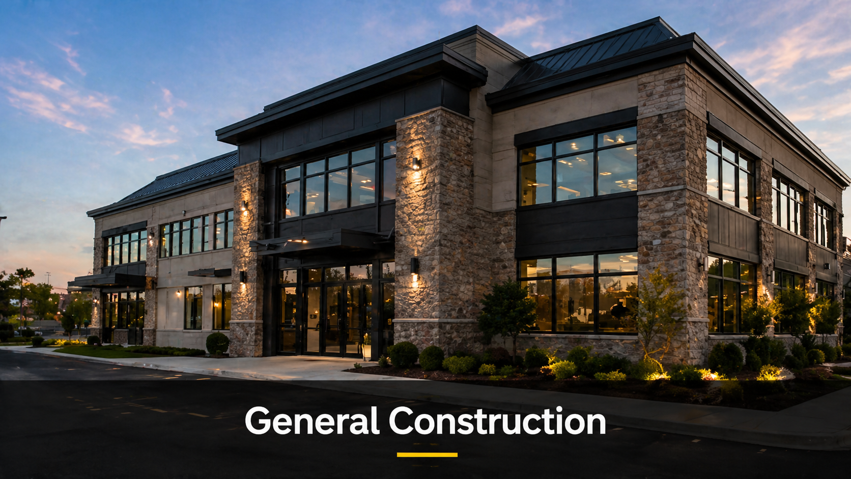 Exterior of a modern two-story commercial building with large glass windows, stone and dark panel accents, and landscaped surroundings at sunset.