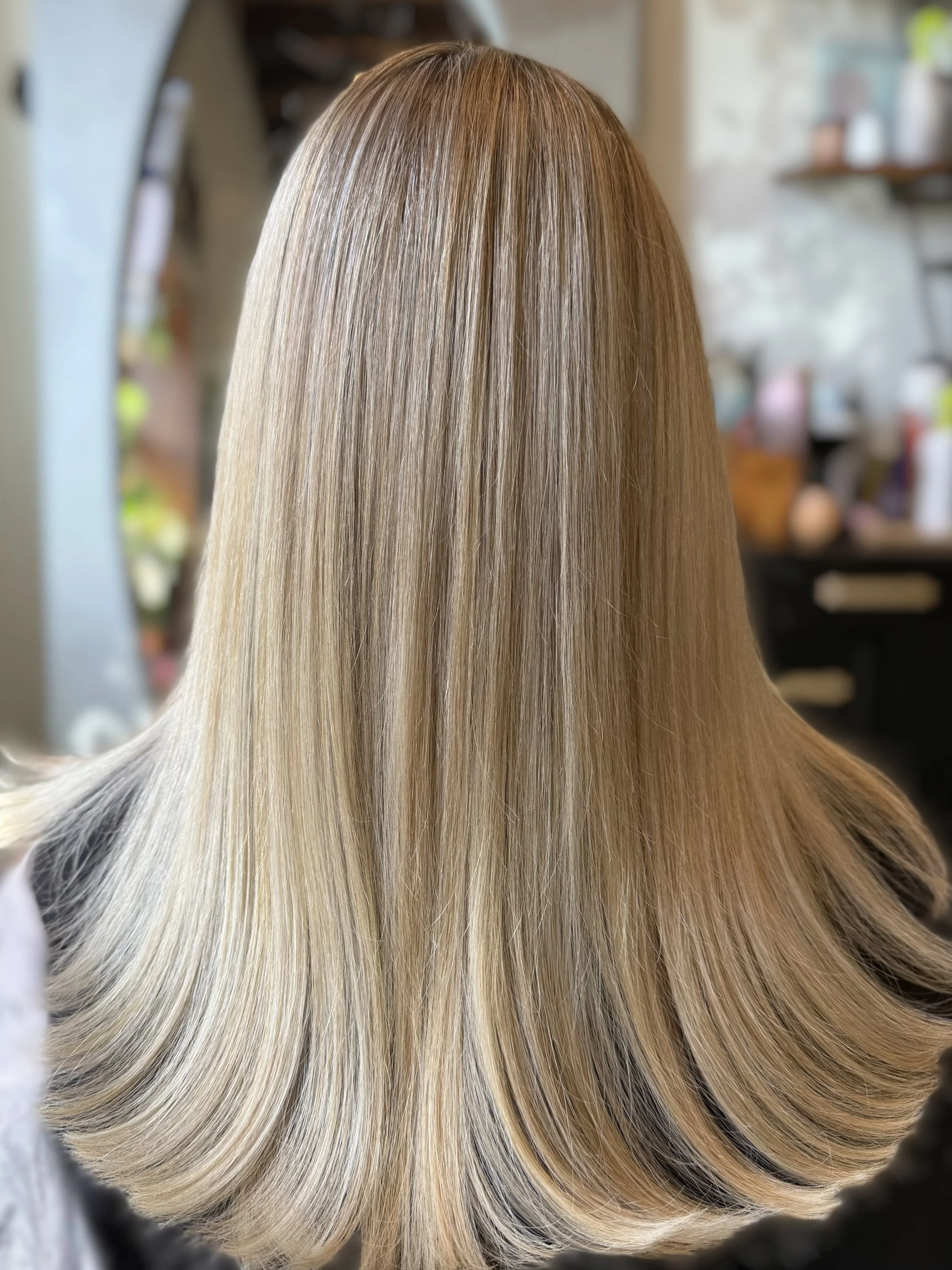Close-up of long, straight, blonde hair with subtle highlights, flowing smoothly and shiny.