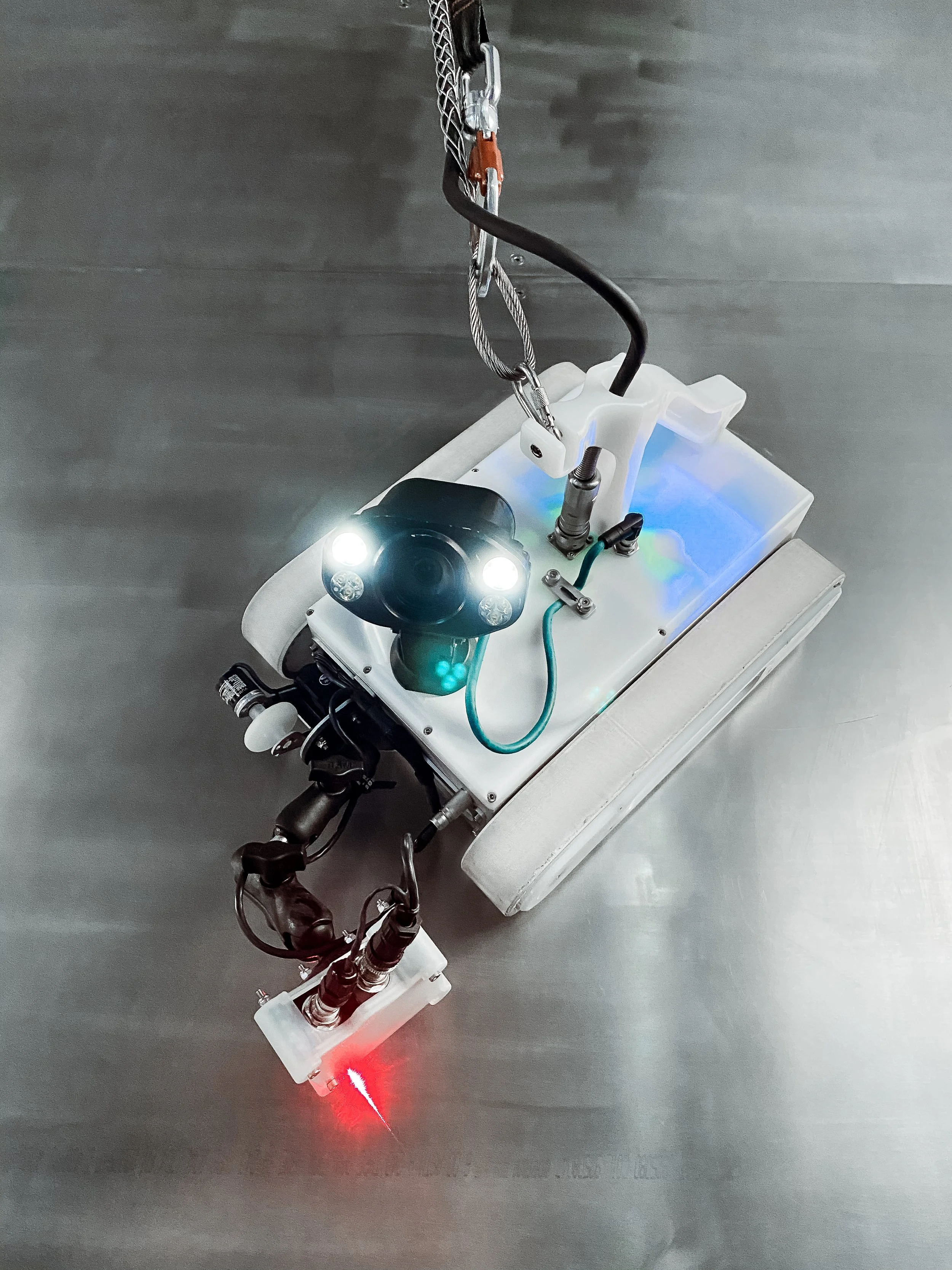 Close-up of an Invert Robotics robotic, with laser surface scanner tool and lights on a stainless steel surface.