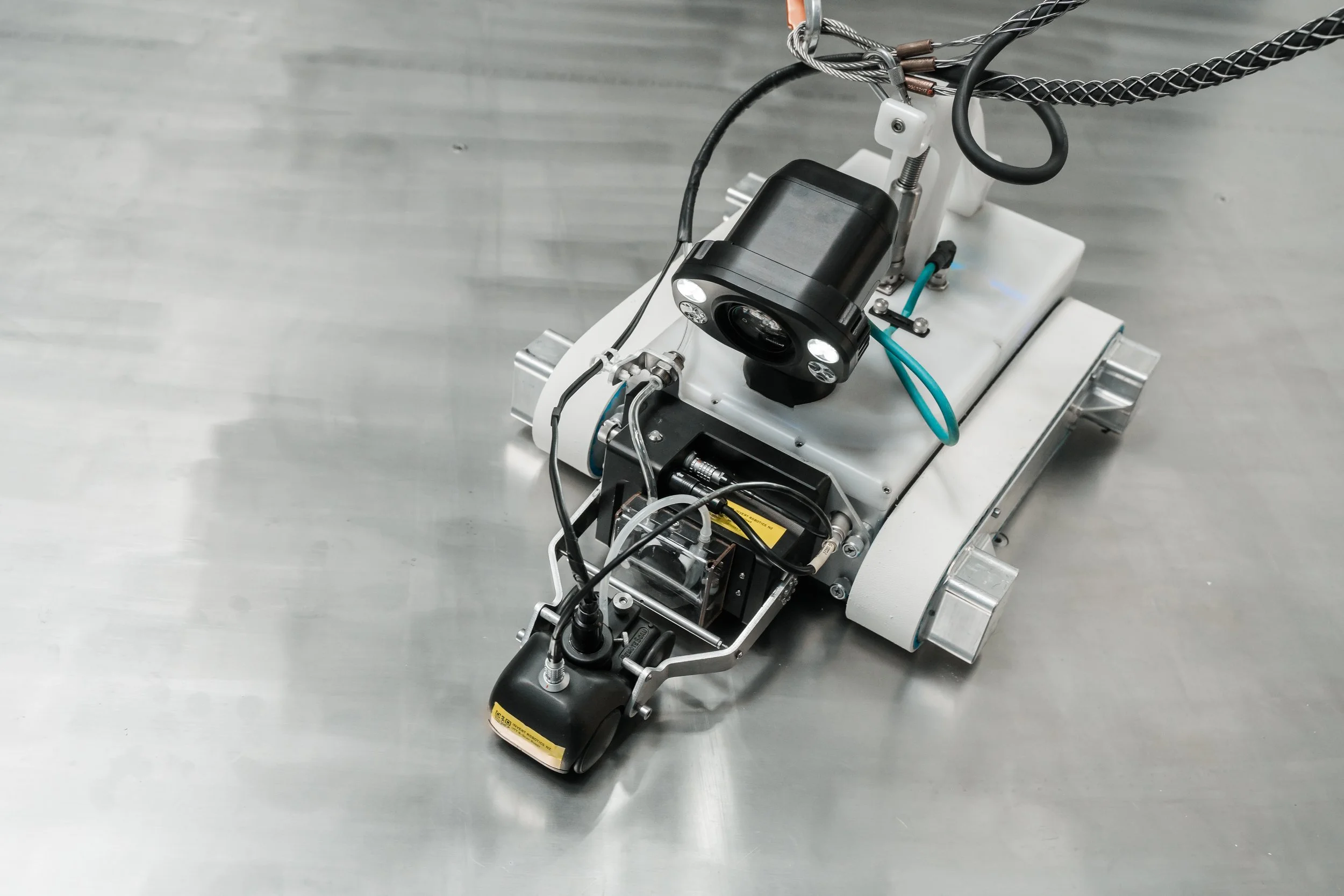 Close-up of an Invert Robotics robotic, with Ultrasonic thickness tool and lights on a stainless steel surface.