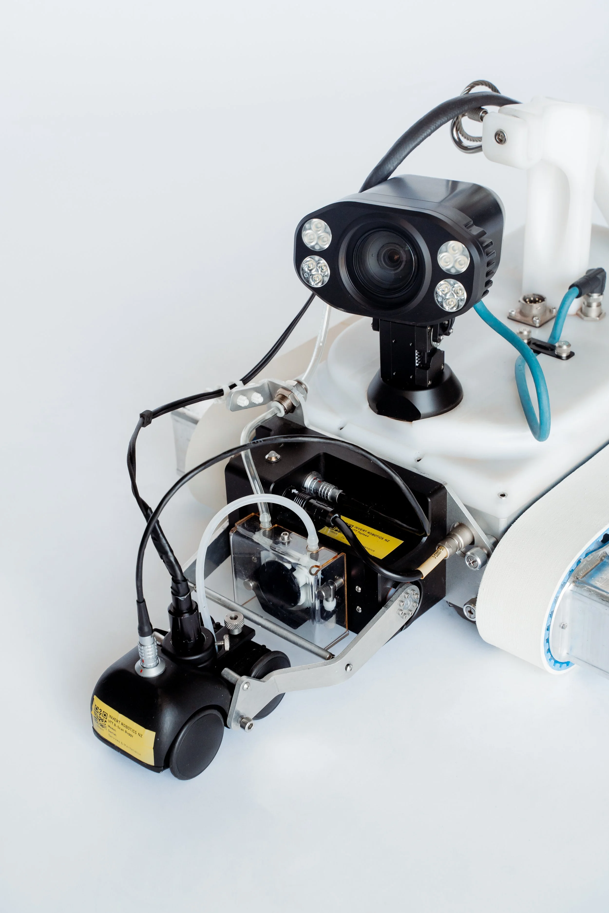 Close-up of an Invert Robotics robotic, with Ultrasonic thickness tool and lights on a stainless steel surface against a plain background.