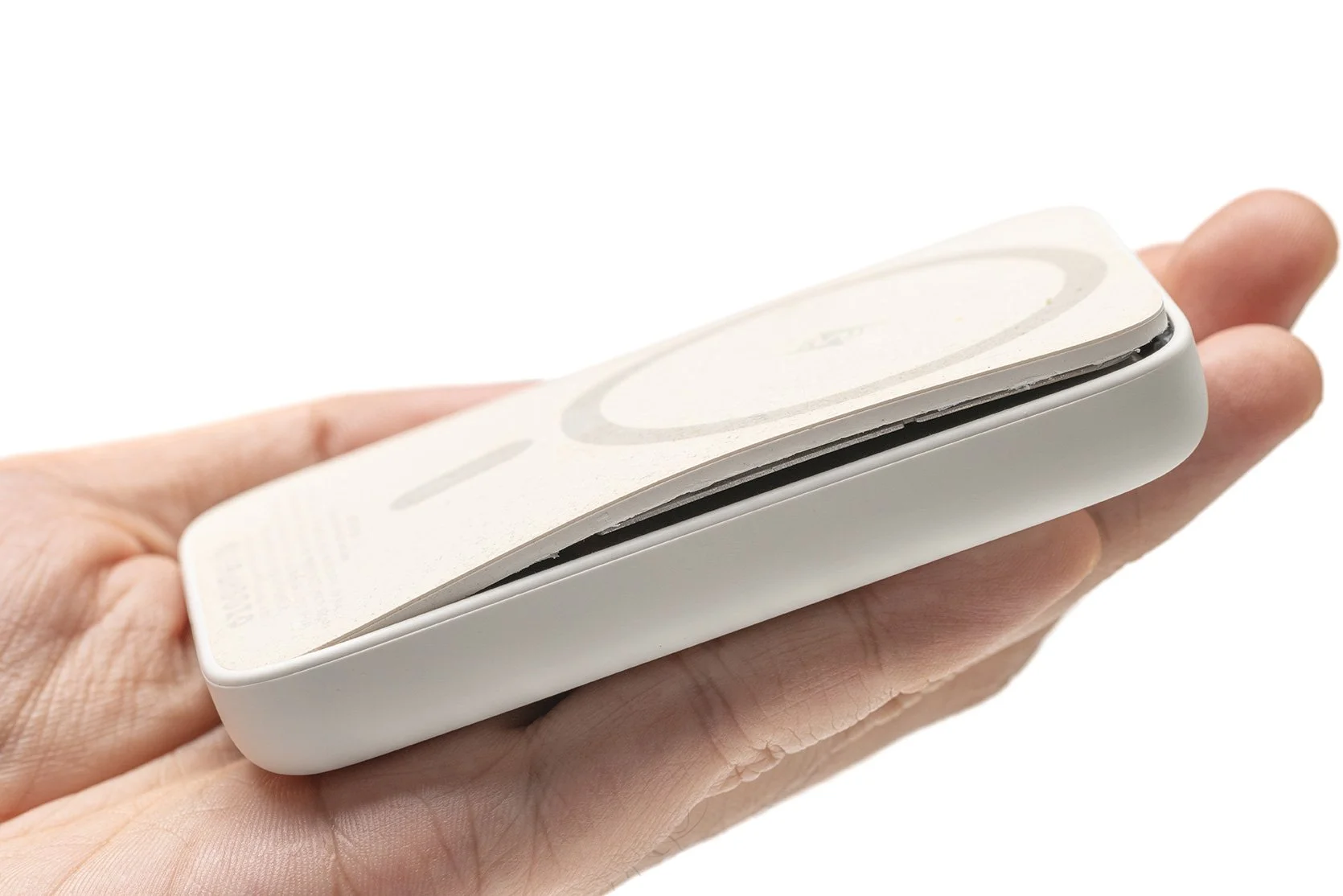 A person's hand holding a white, rectangular device with a circular logo on its surface.