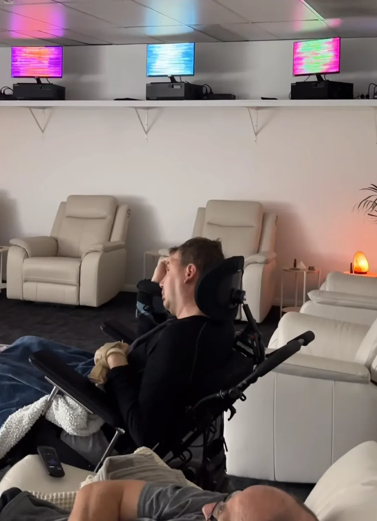 Person in wheelchair relaxing in Soulibrium sensory session room with colourful screens and Himalayan salt lamp