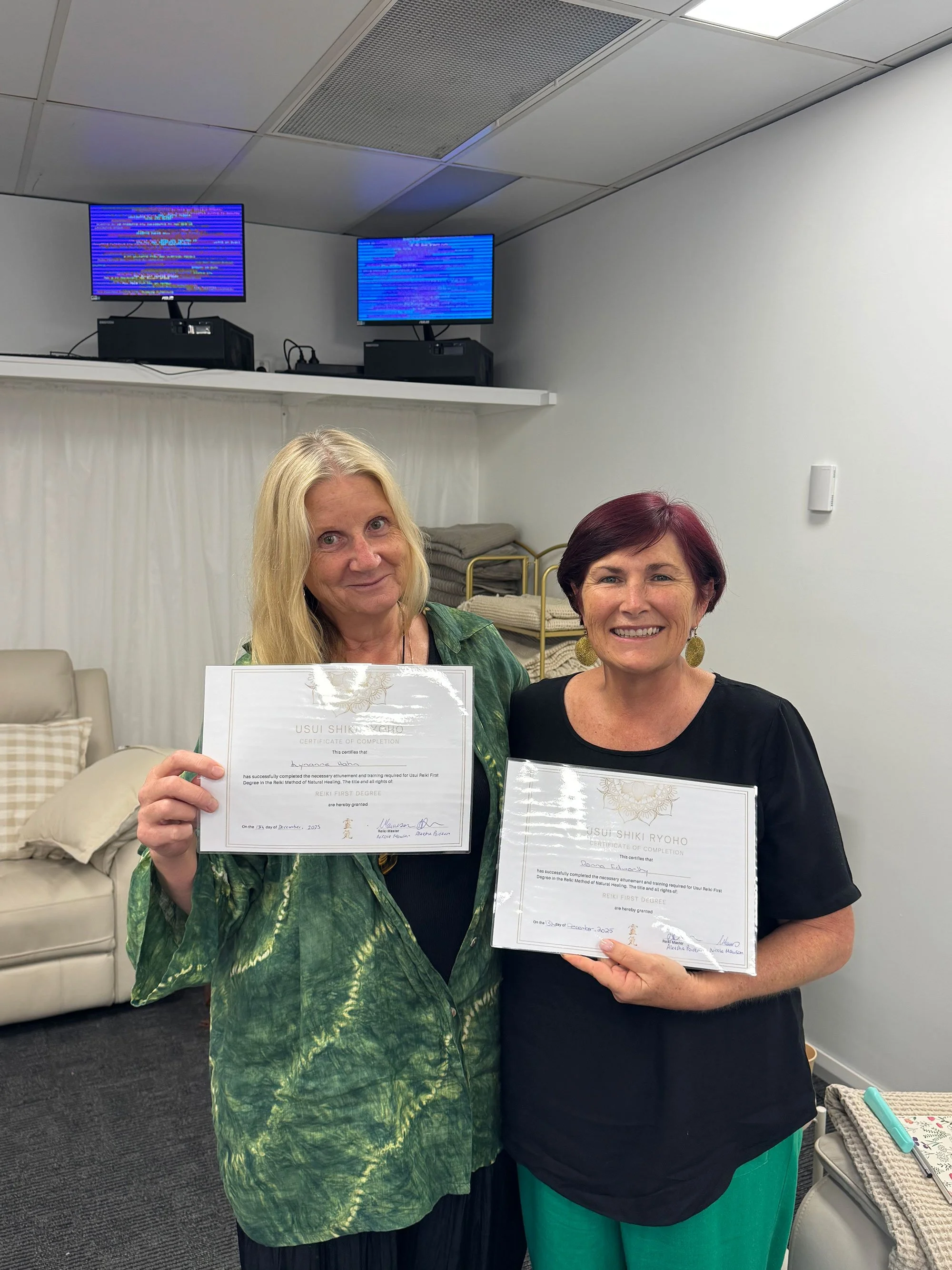 Two women smiling and holding Usui Shiki Ryoho reiki certificates after completing Soulibrium reiki training