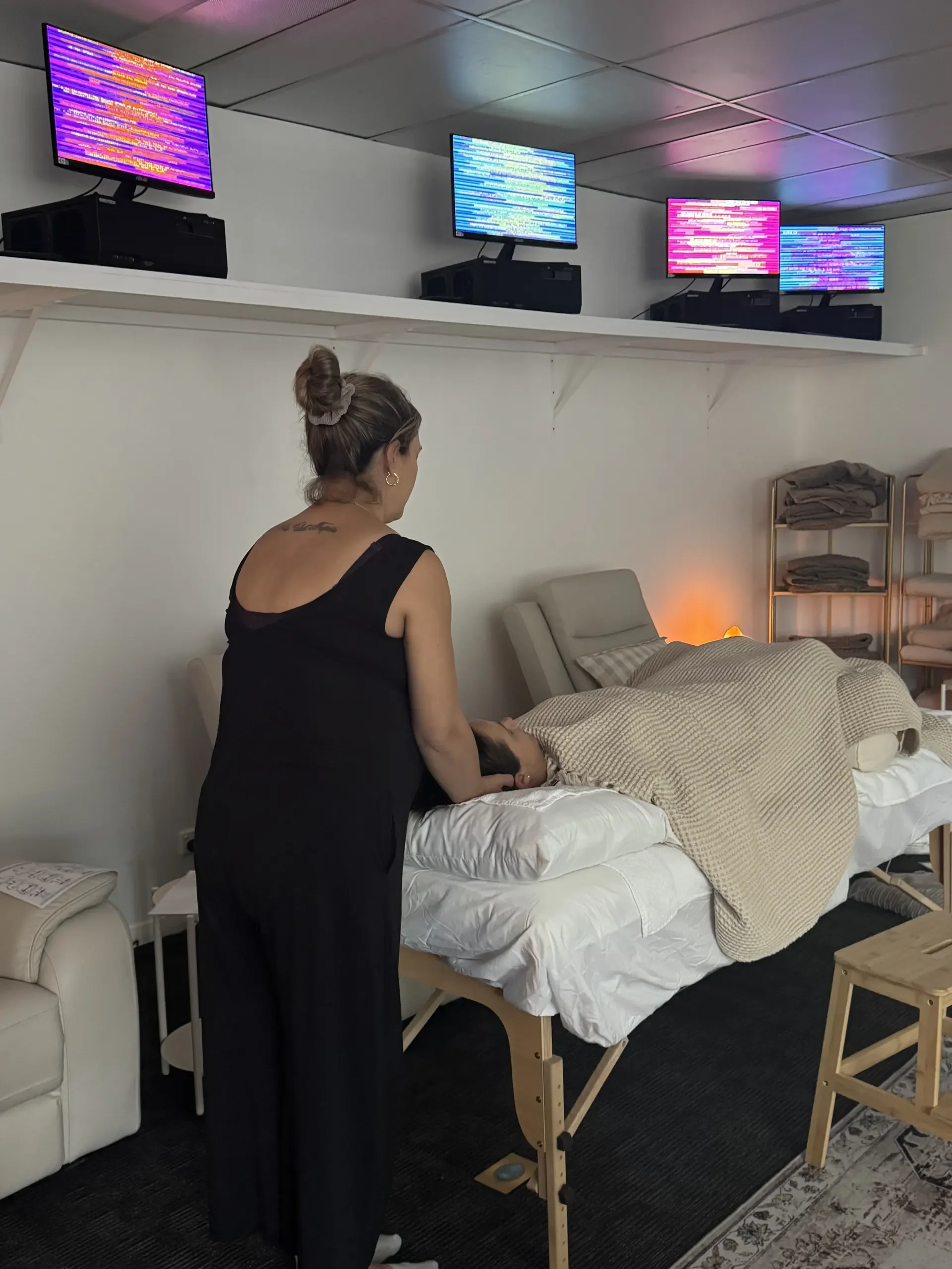 Reiki practitioner placing hands gently on client's crown during a treatment session in the Soulibrium Scalar wellness room