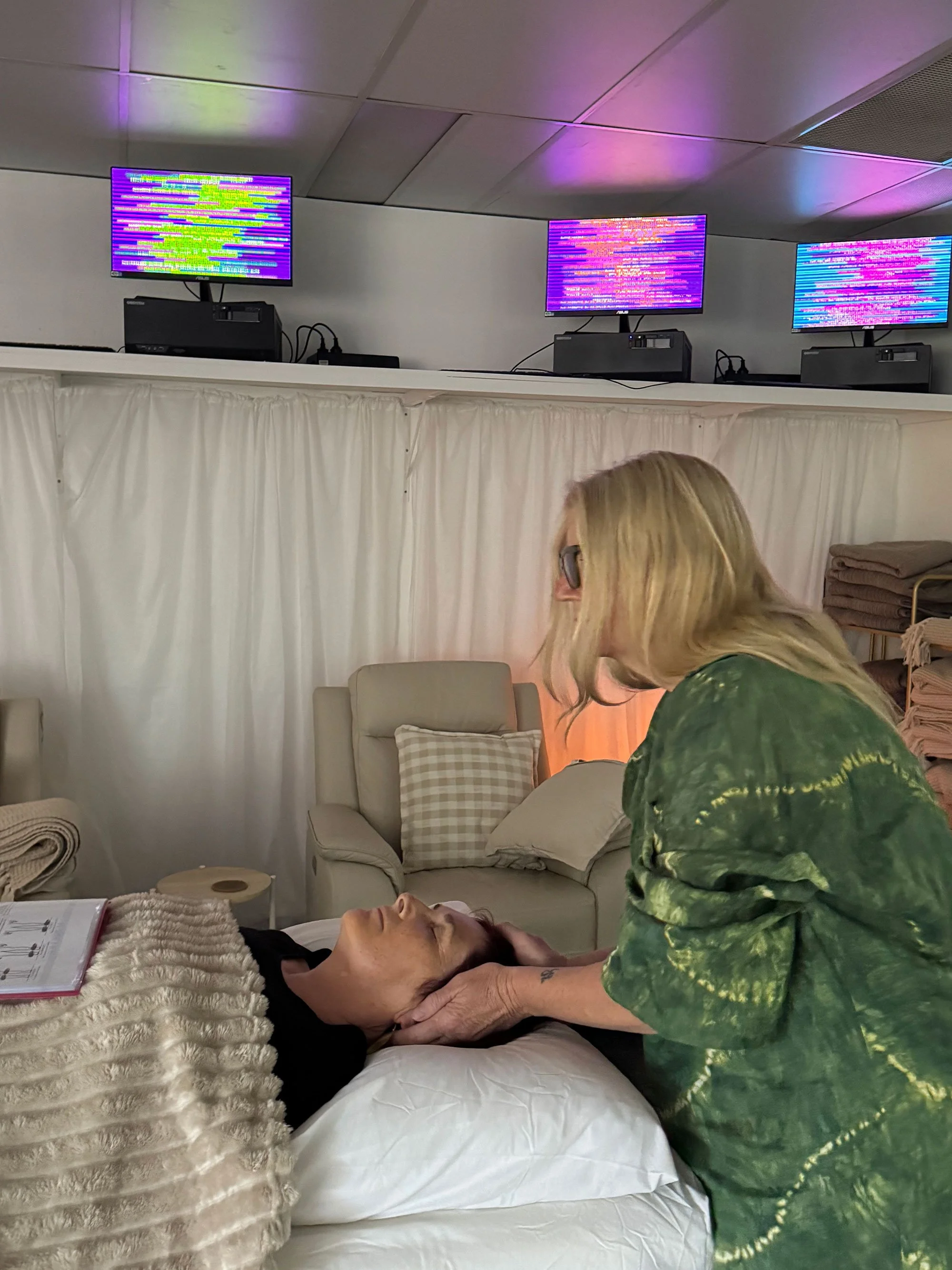 Reiki practitioner placing hands gently on client's crown during a treatment session in the Soulibrium Scalar wellness room