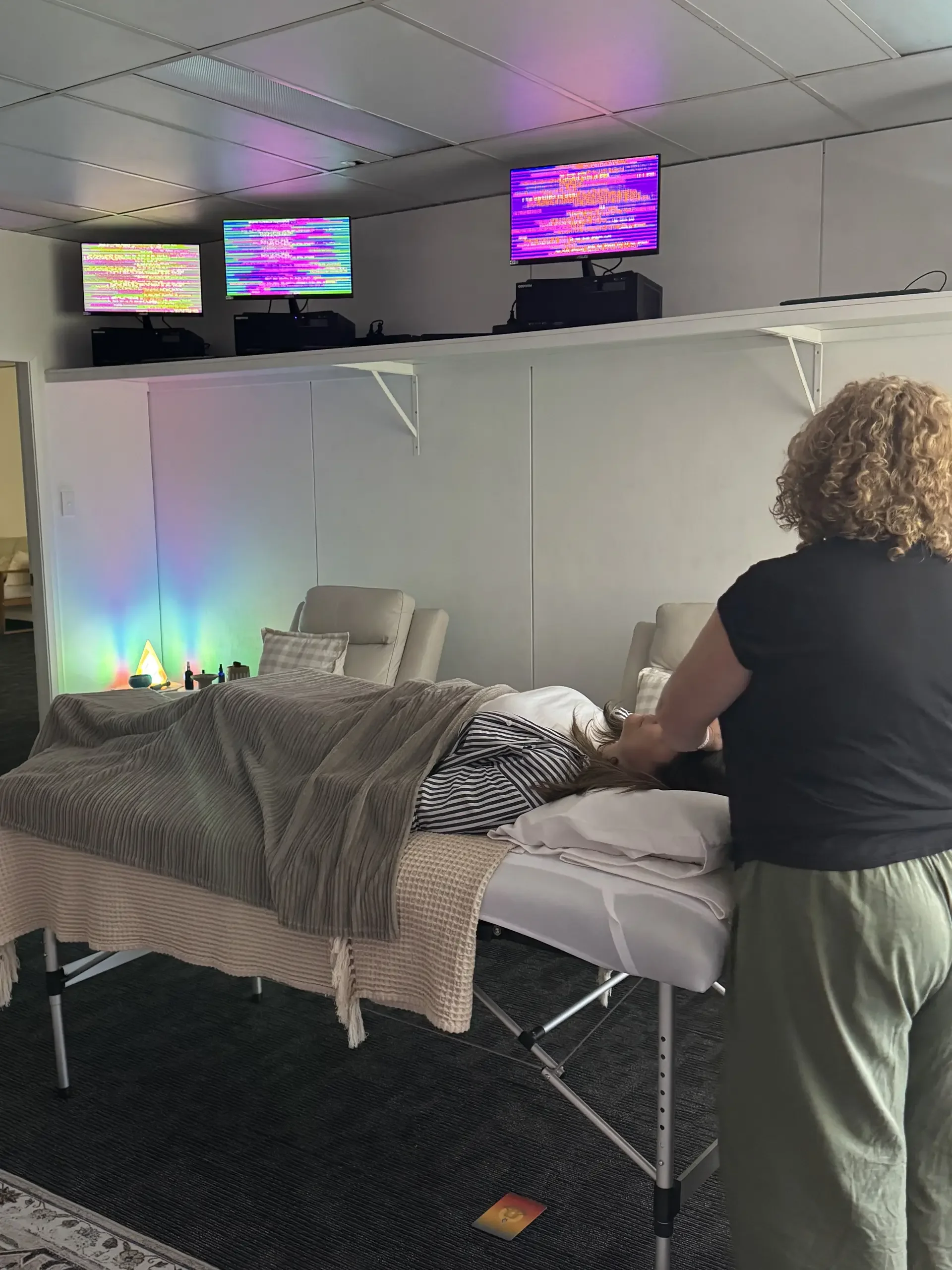Reiki student performing head position on client at treatment table in the Soulibrium Scalar wellness room