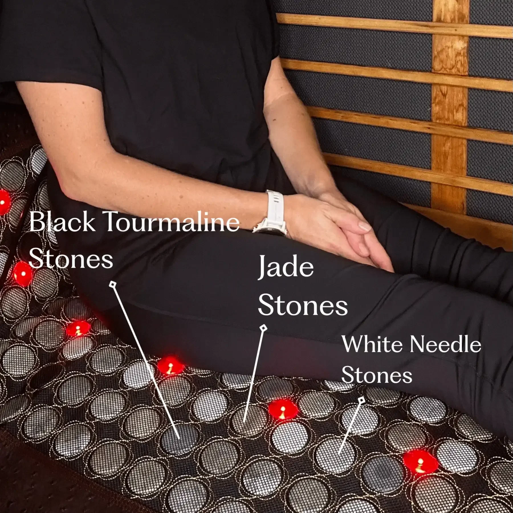 Seated person on Soulibrium PEMF mat with callouts labelling black tourmaline stones, jade stones and white needle stones