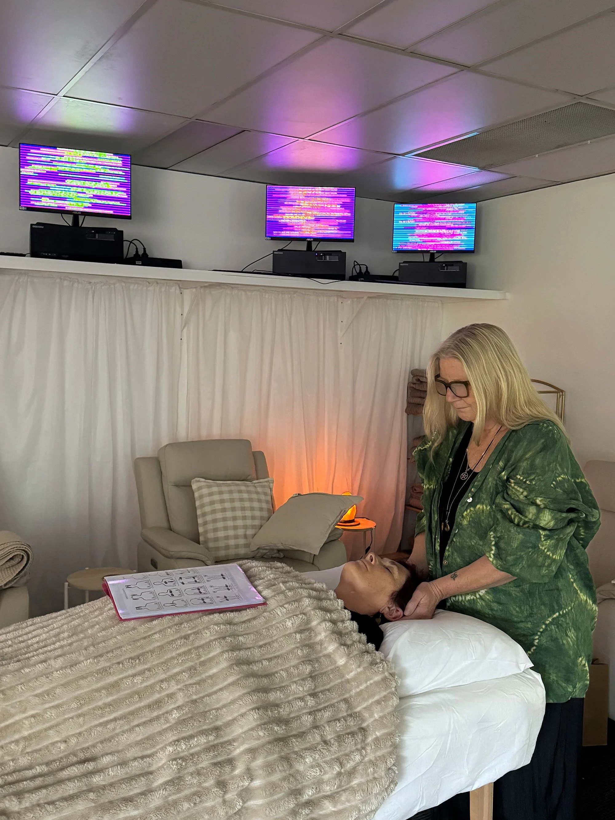Reiki student with reference guide performing head position on client during Soulibrium training session