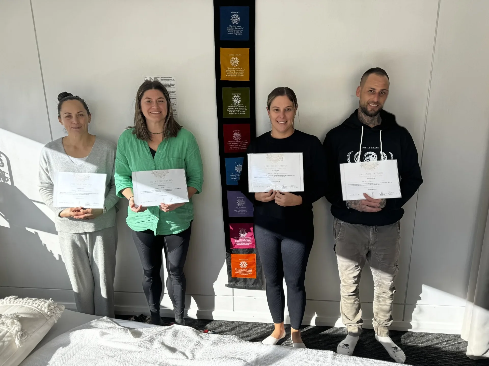 Four Soulibrium reiki training graduates smiling and holding their completion certificates