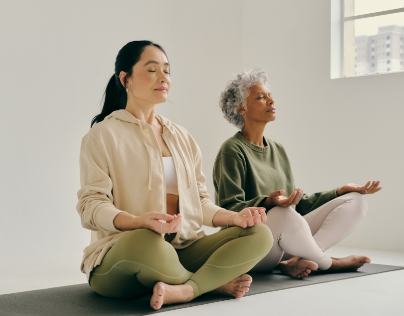 Two Women sitting cross-legged on yoga mats enjoying a Soulibrium Meditation session