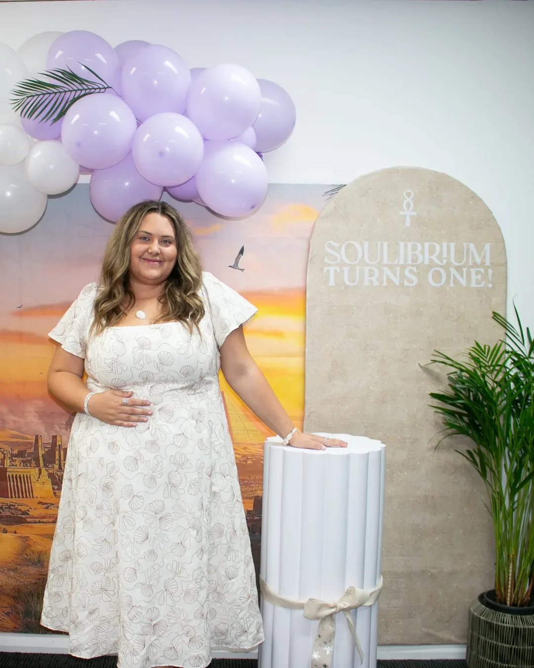 Aleesha at Soulibrium Turns One anniversary event with purple and white balloon arch