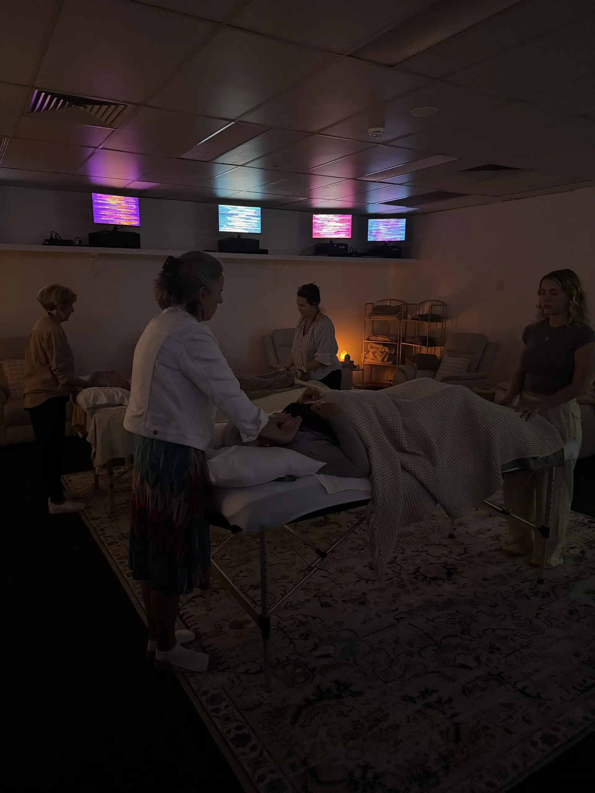Practitioners performing energy healing on clients lying on treatment tables in Soulibrium Scalar wellness room