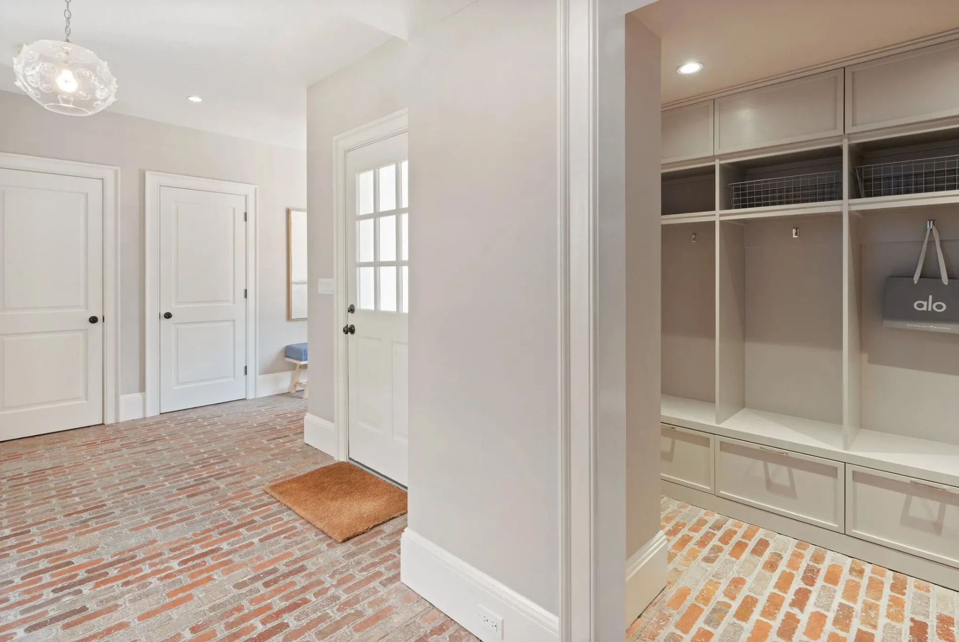 Darien Connecticut mudroom and entry hallway after renovation by Ginger Lemon Indigo, showing brick floor, recessed lighting and custom built-in storage