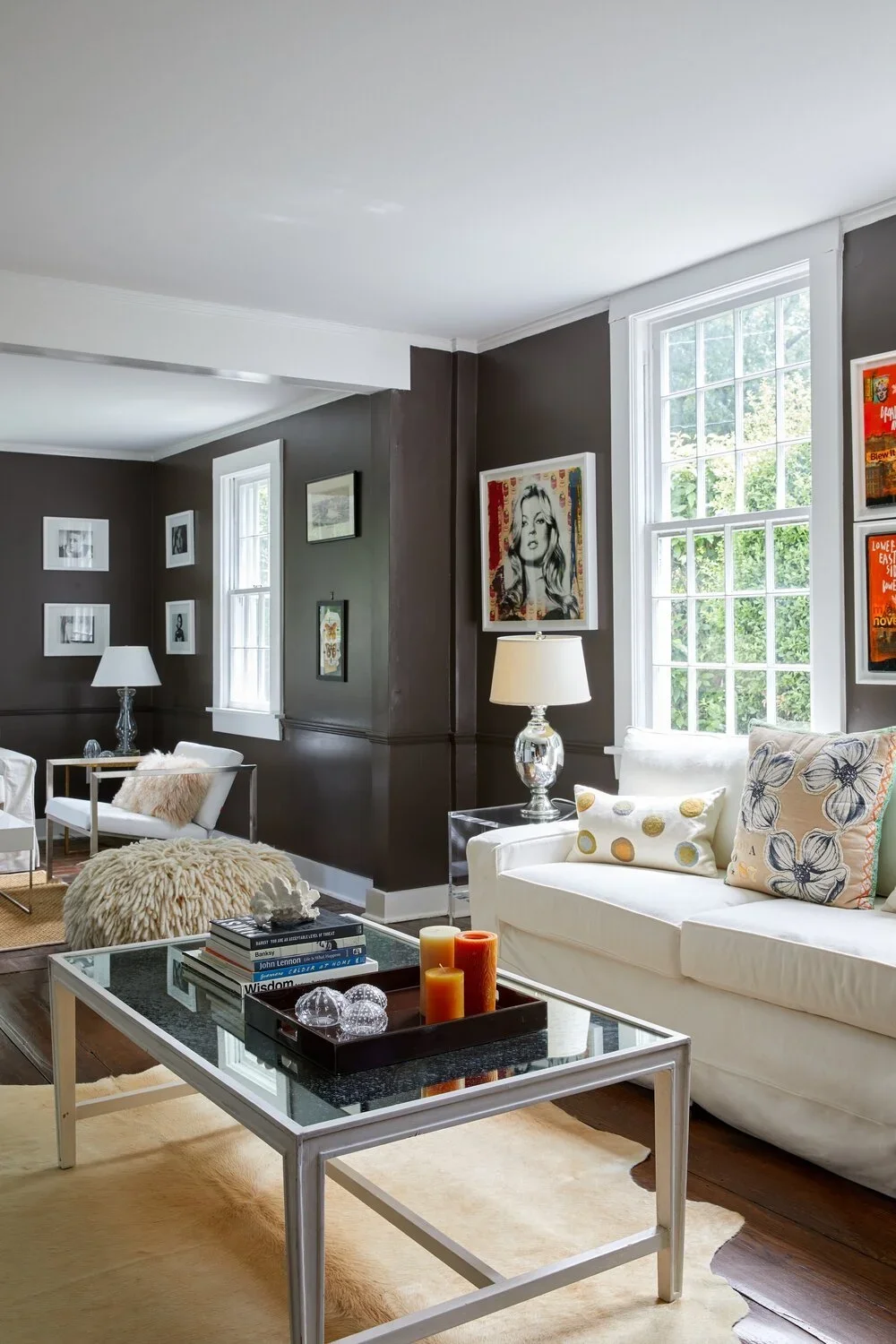 Eclectic living room with dark brown walls, layered art collection, white sofas, and vintage accessories in a Darien CT farmhouse by Ginger Lemon Indigo