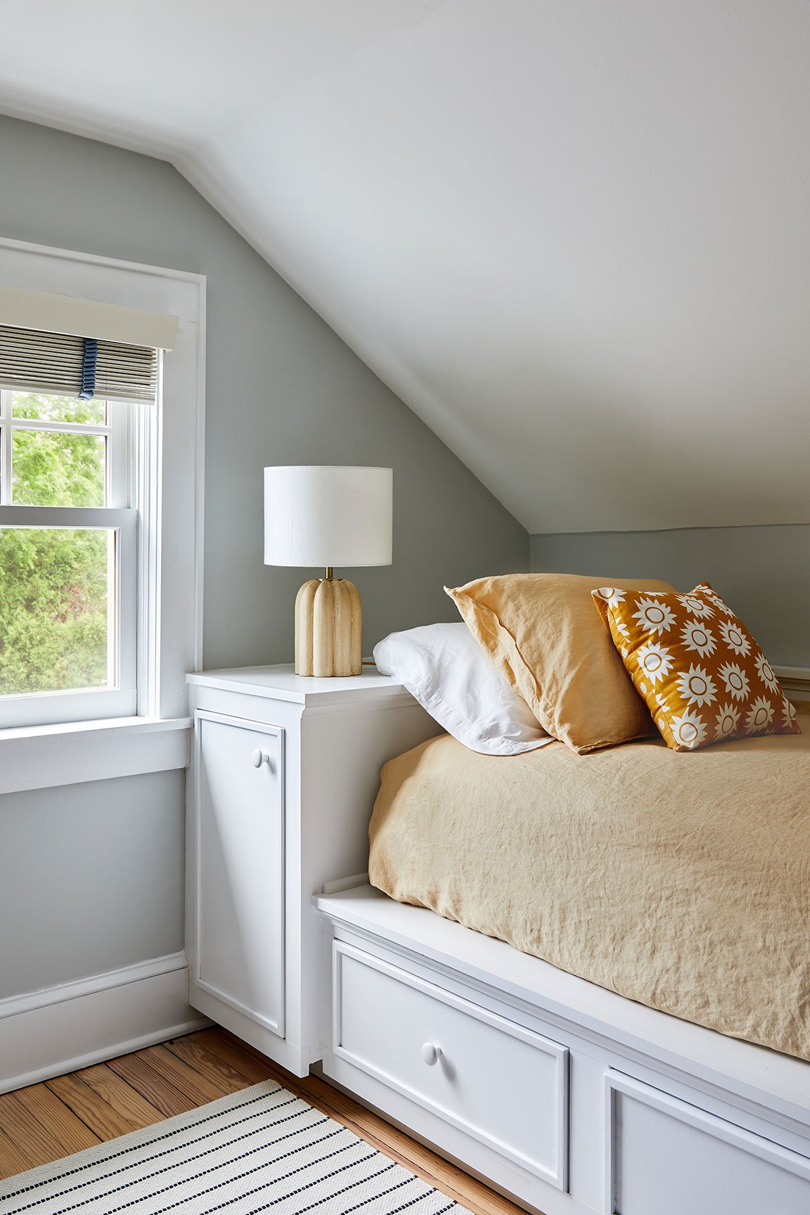 Kids bedroom with built in storage bed, mustard bedding, sunflower pillows, and sculptural ceramic lamp in a Southampton NY home by Ginger Lemon Indigo