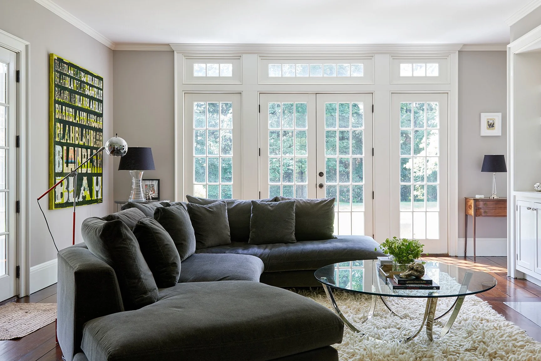 Eclectic family room with charcoal velvet sectional, vintage glass coffee table, shag rug, and bold pop art canvas in a Darien CT farmhouse by Ginger Lemon Indigo