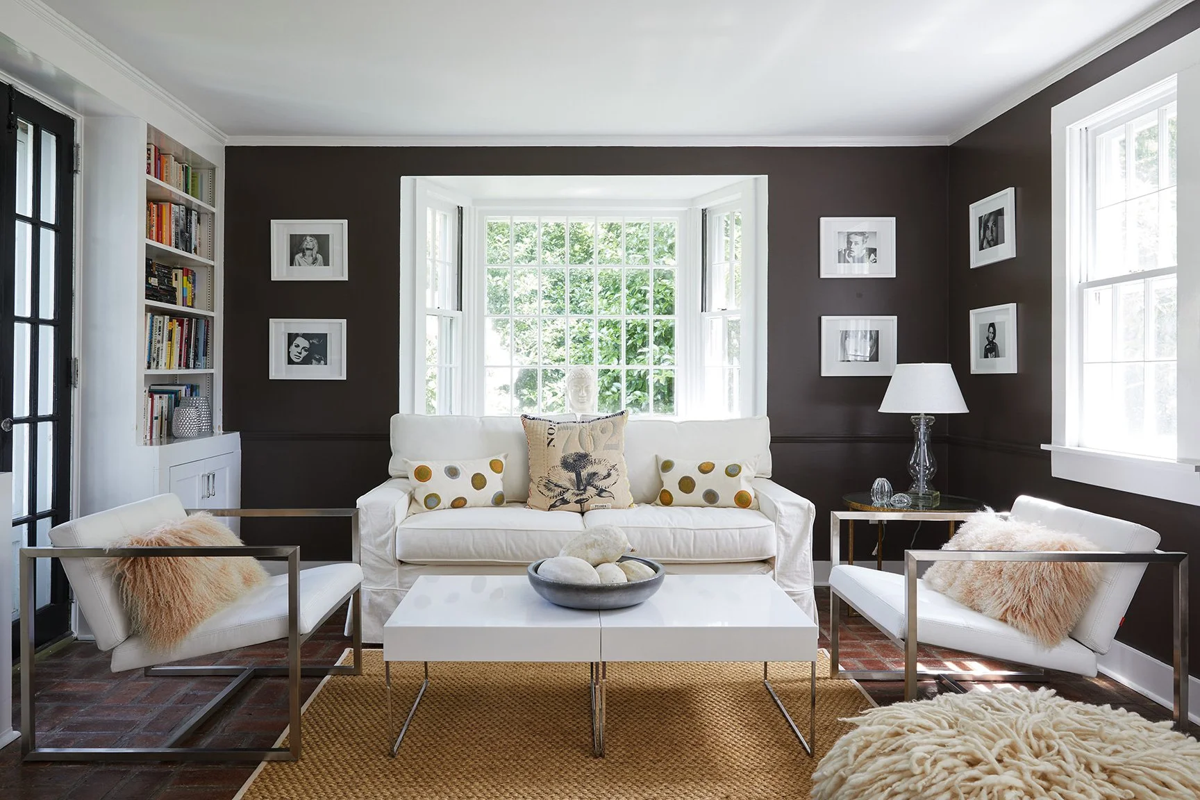 Nearby Darien CT living room with chocolate walls, white slipcover sofa, gallery of black-and-white portraits, built-in bookshelves and jute rug