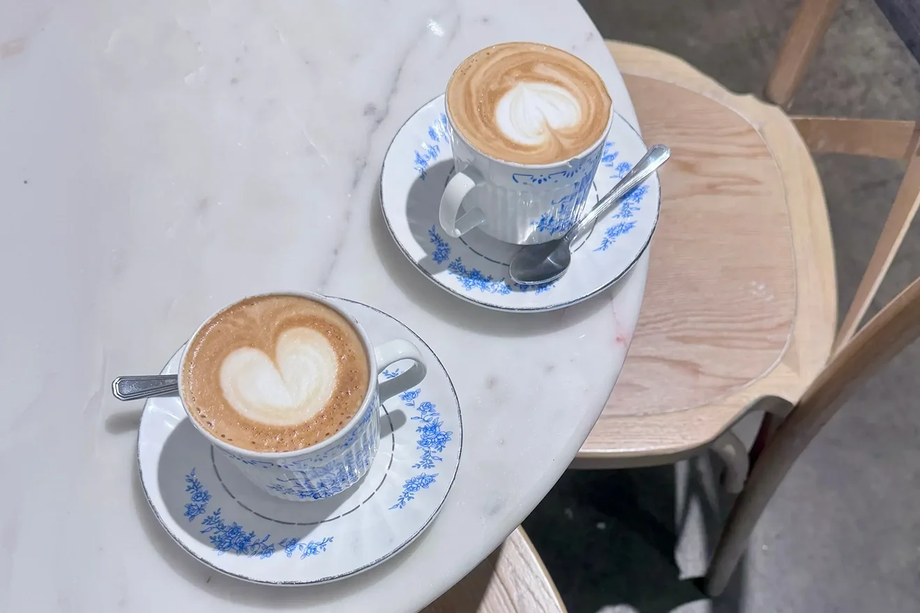 Two cappuccinos on a marble countertop, blue floral porcelain cups
