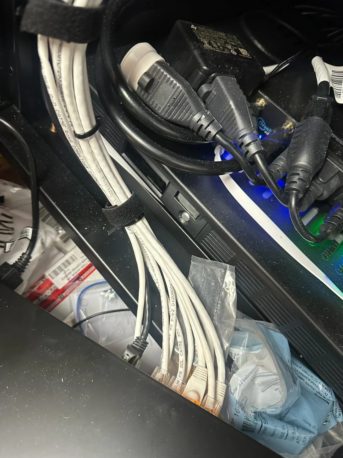 Close-up of electronic equipment with multiple cables and power adapters connected, some secured with velcro straps.