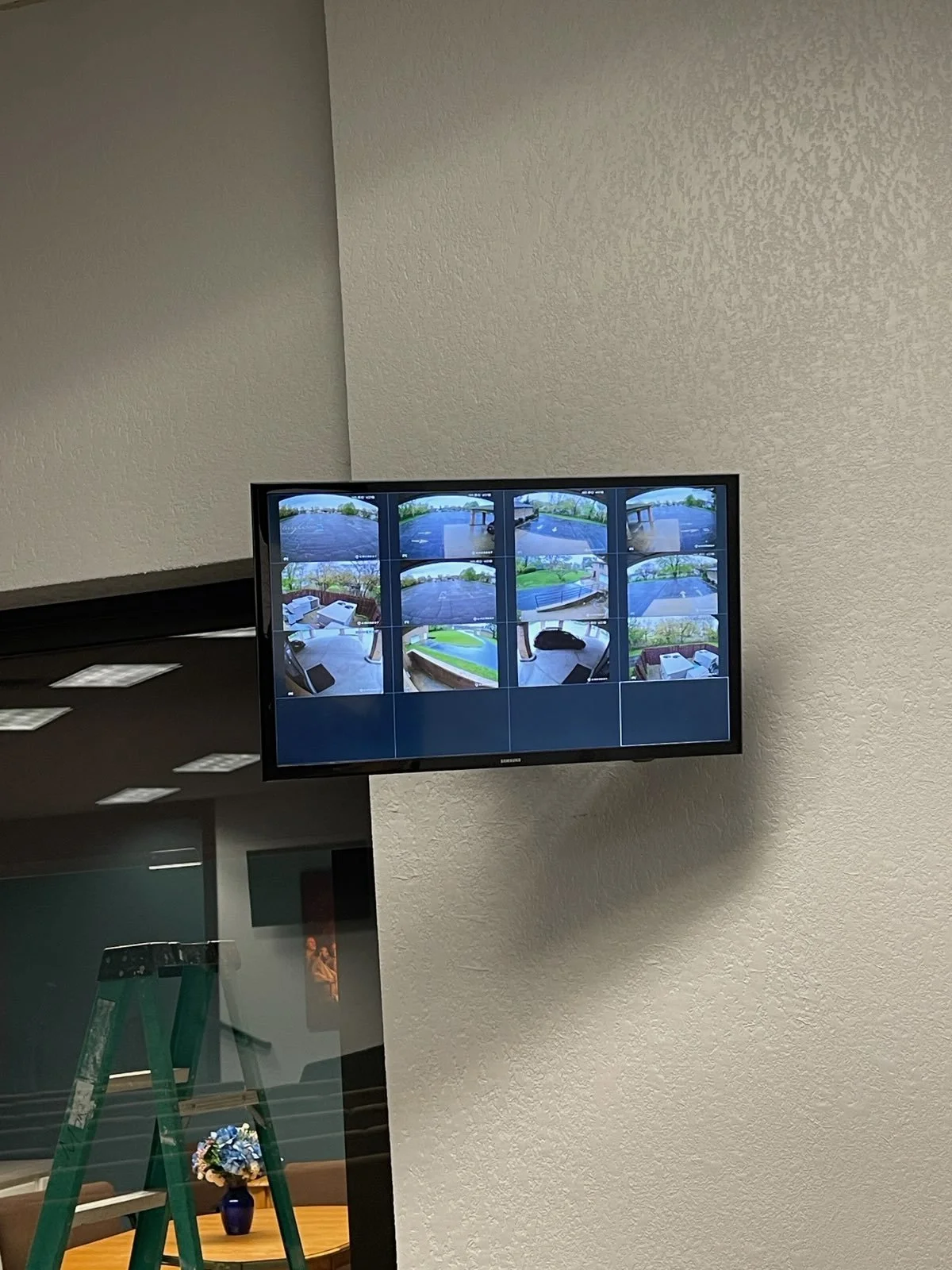 Surveillance monitor displaying multiple camera feeds of outdoor and indoor areas.