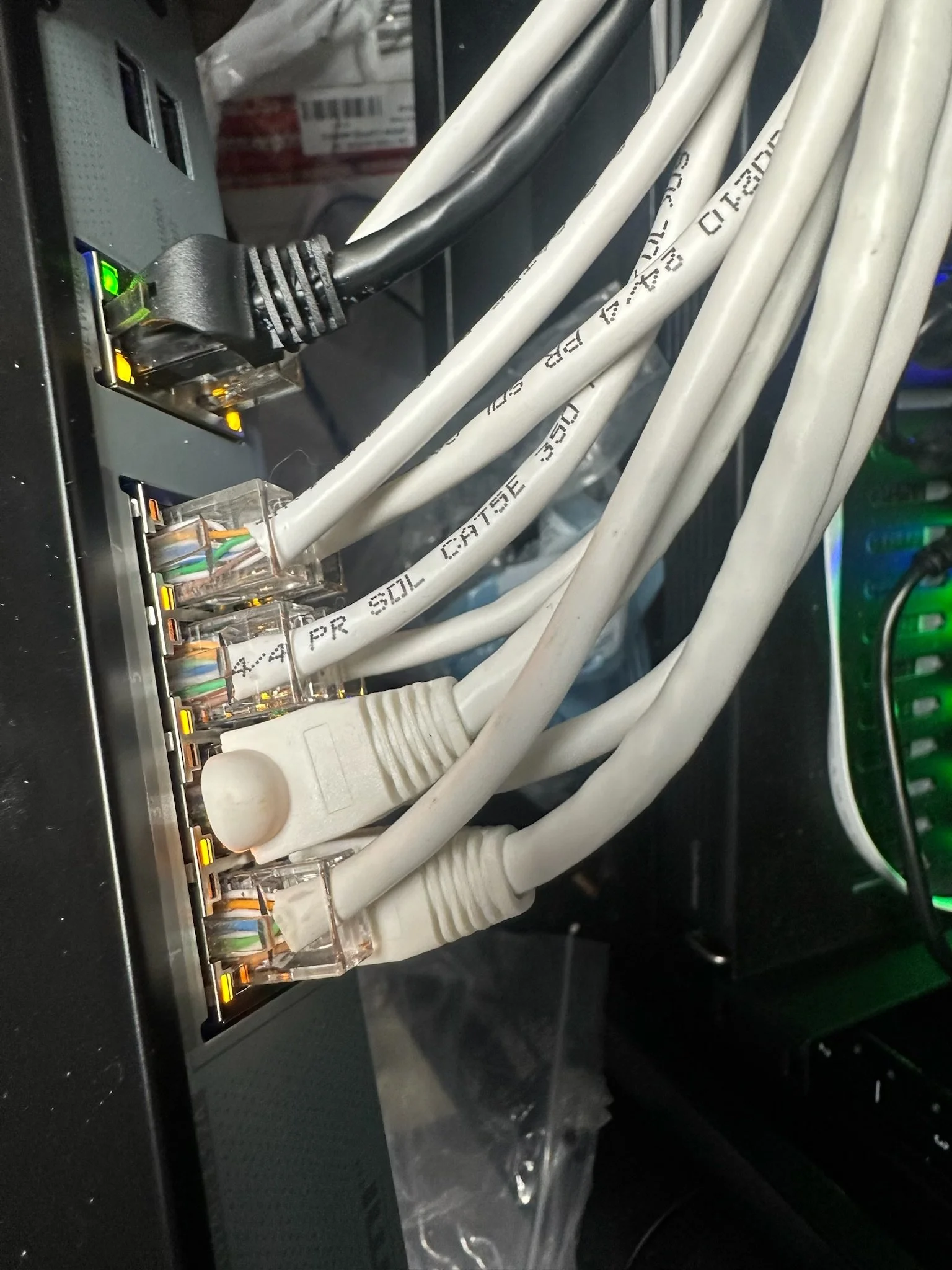 Close-up of multiple white Ethernet cables plugged into a network switch with indicator lights.