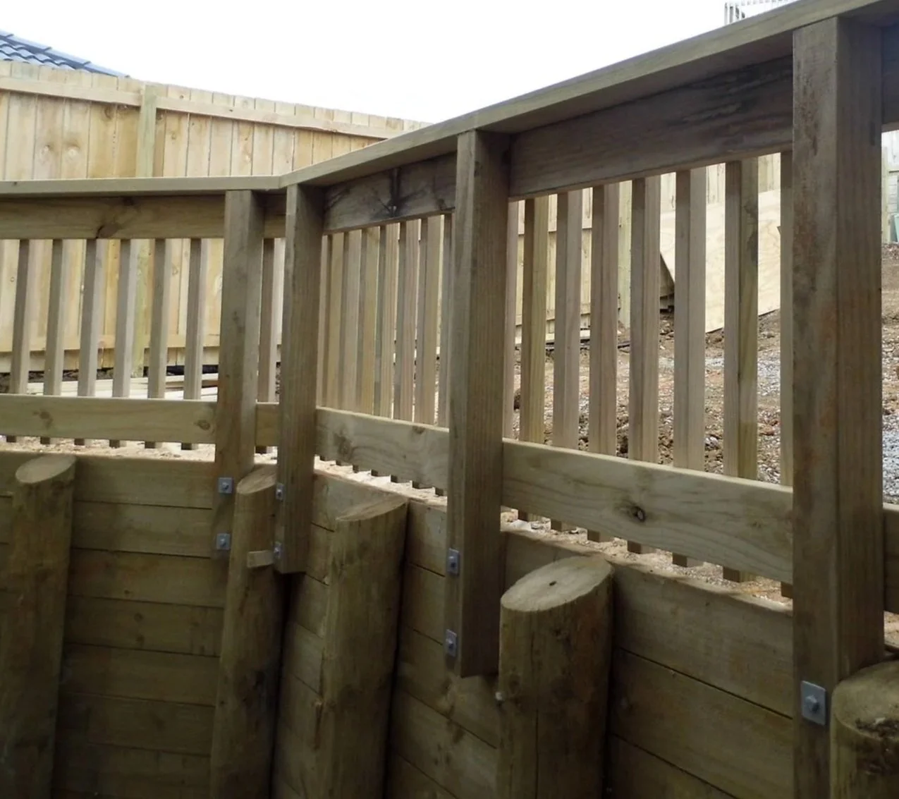 Close-up of a pressure-treated wooden deck railing with vertical balusters and a smooth top handrail, showing natural wood grain and texture created in Pukekohe
