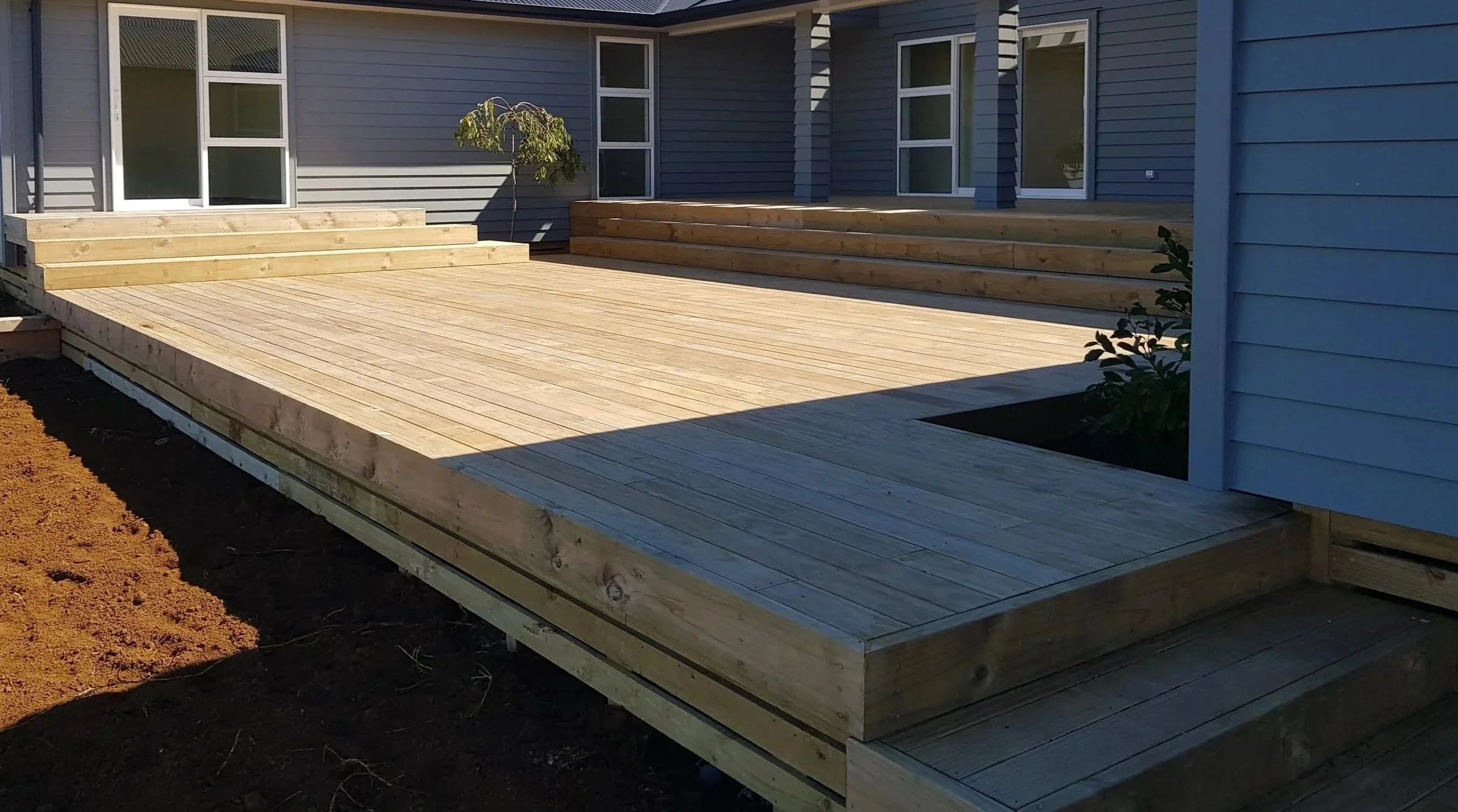 Custom two-tier treated pine wooden deck newly constructed on a large family home in rural Pukekohe, Auckland.