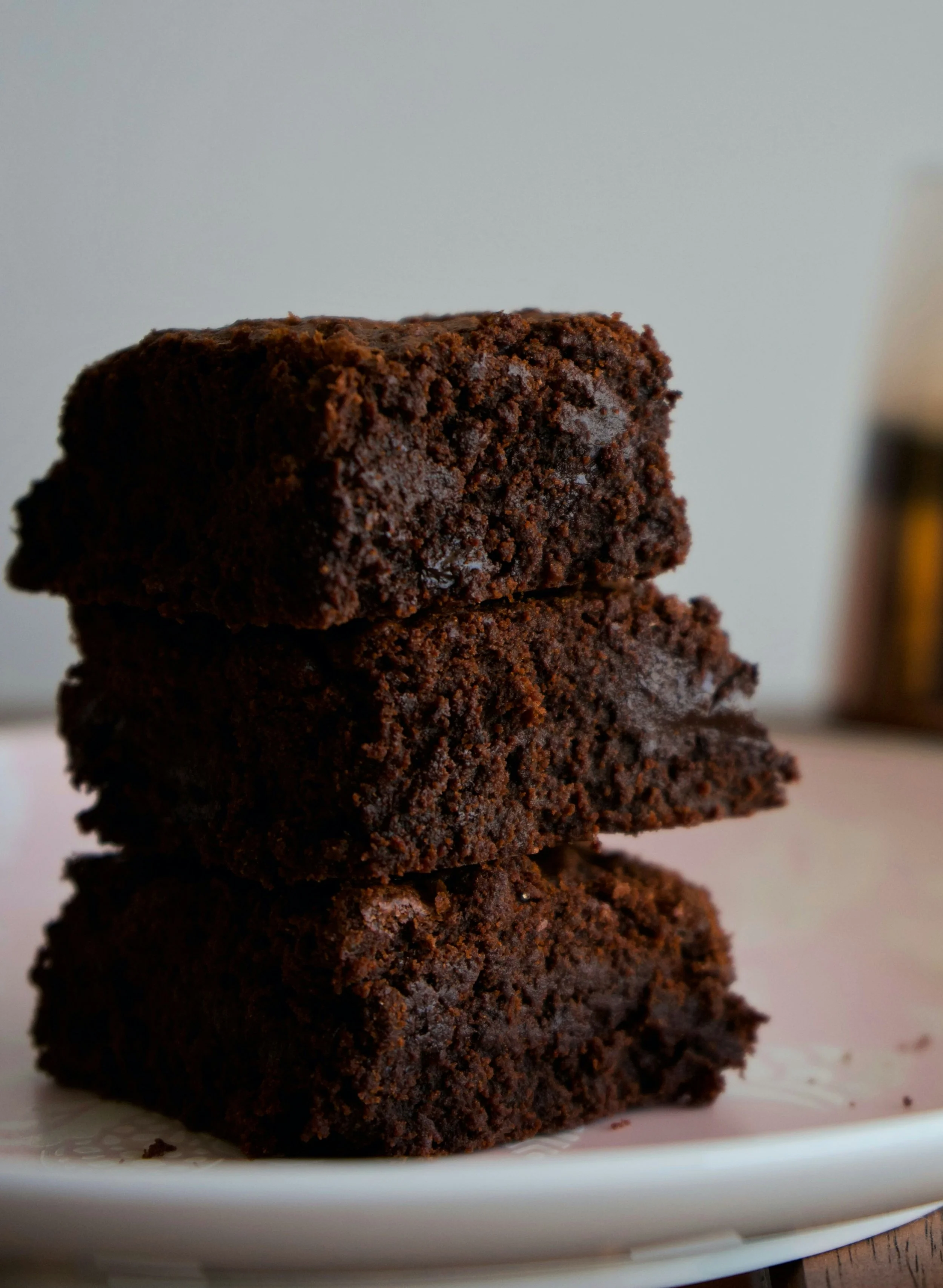 Four stacked chocolate cookies on a white plate.