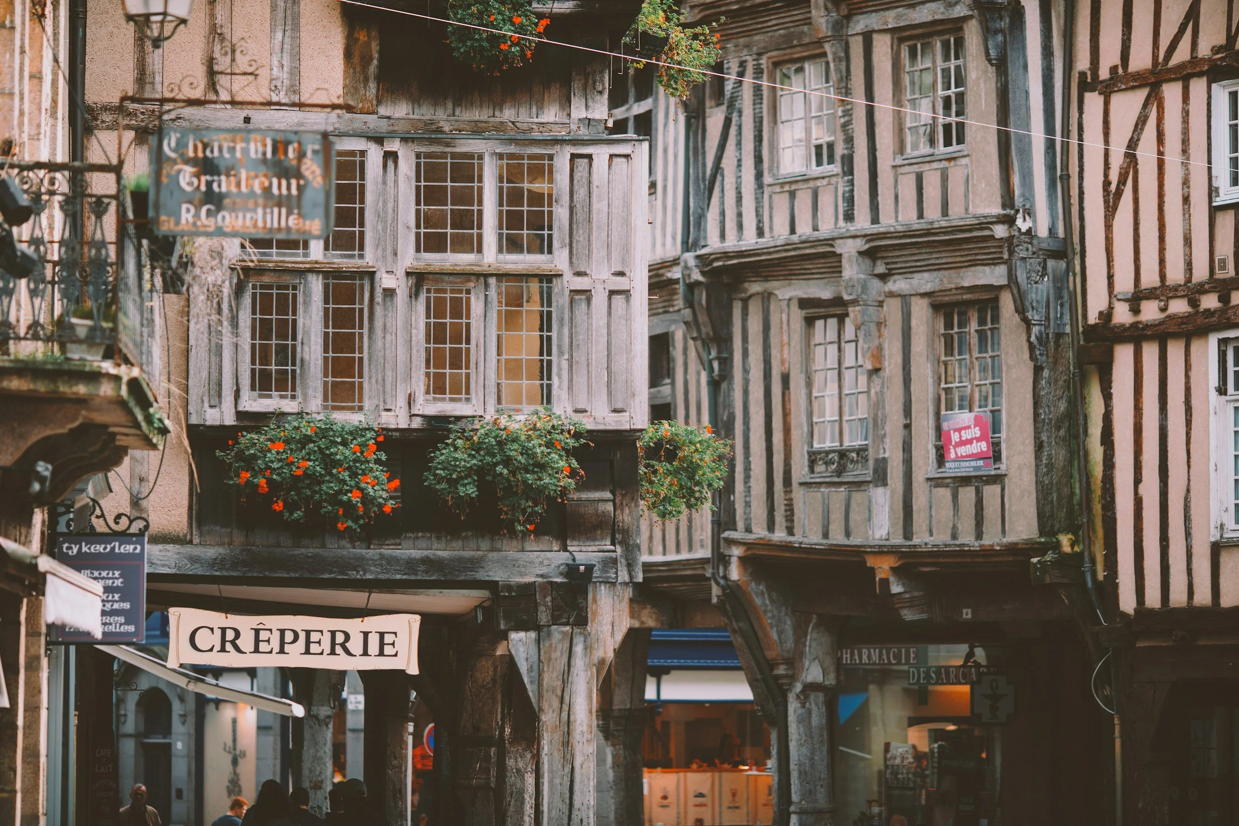Narrow street in France with traditional architecture and a crêperie sign, capturing an everyday European travel moment