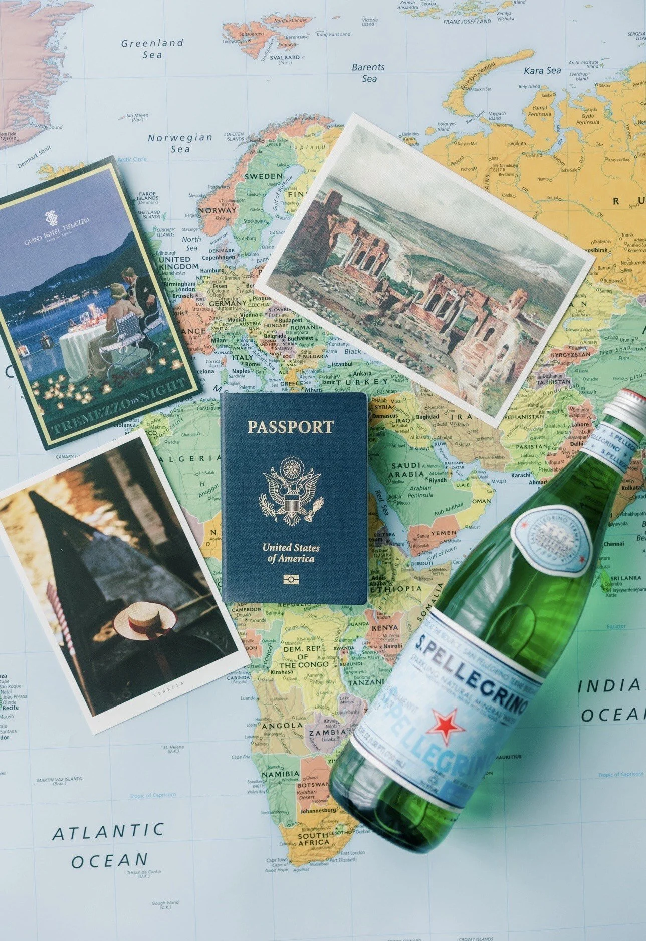 Flat lay of a global travel planning scene featuring a world map, travel documents, and European destination imagery including Italy and Lake Como