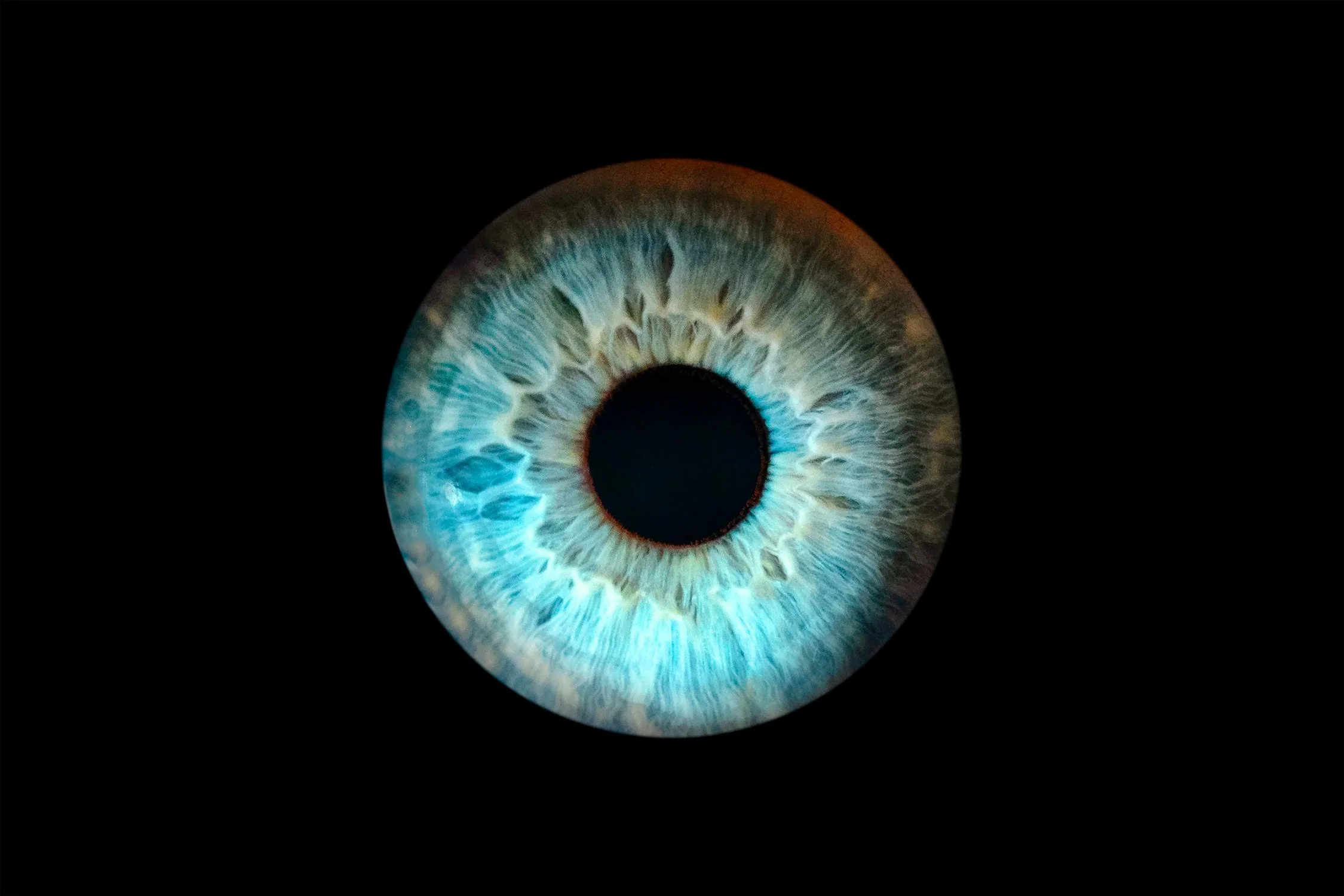 Close-up of a blue and teal human eye, iris filling the frame.