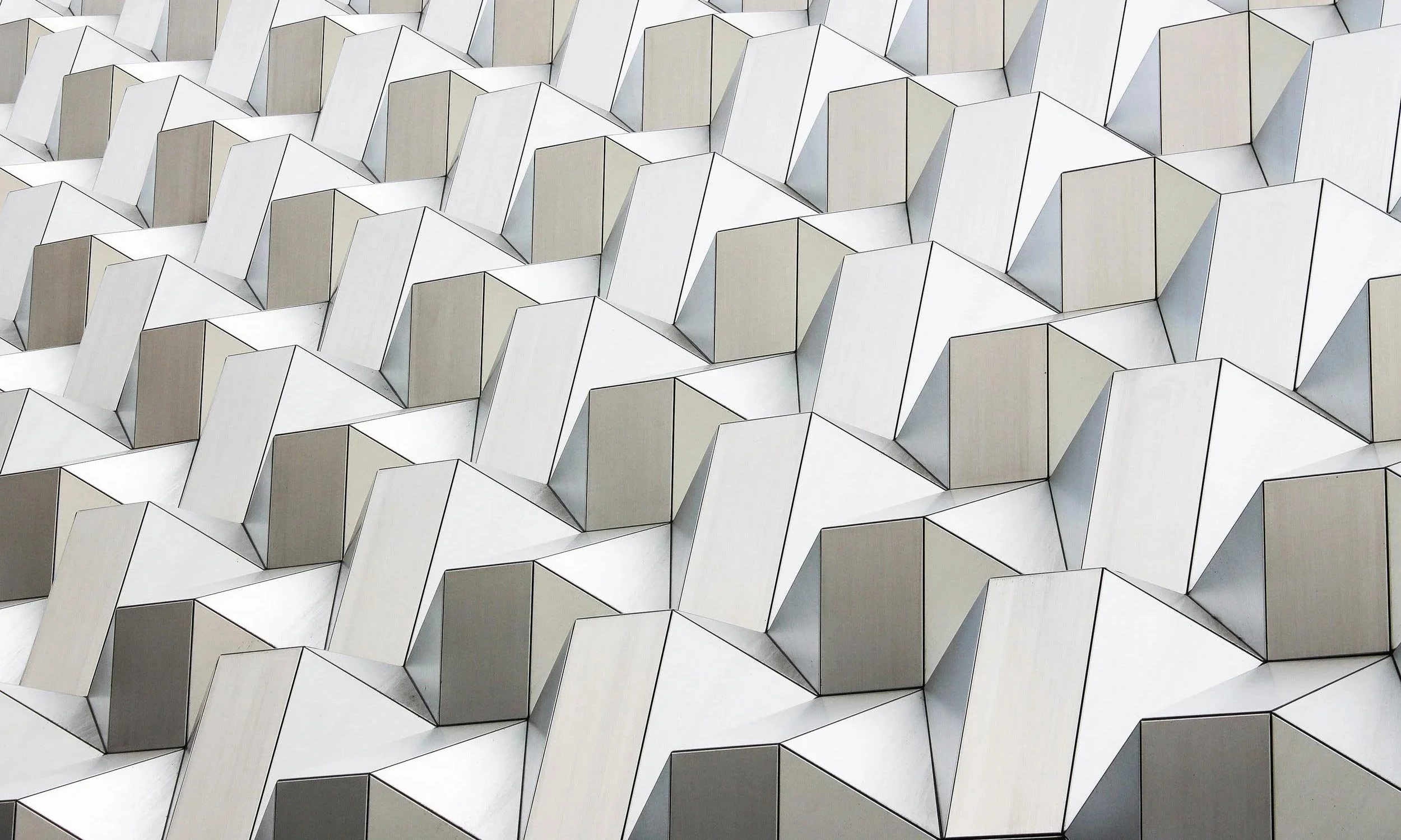 A pattern of repeating angular white three-dimensional geometric shapes.