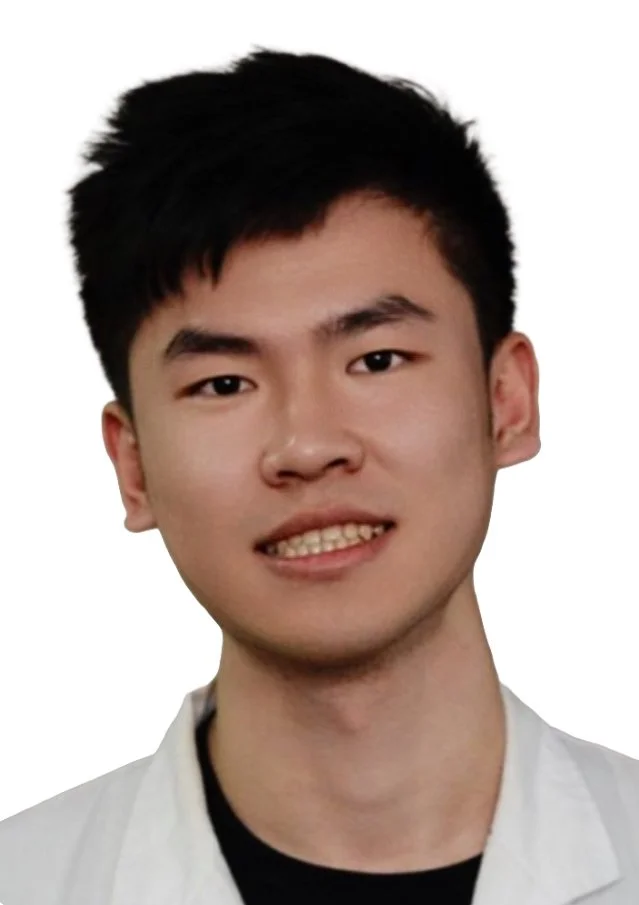 Head and shoulders portrait of a young man with short black hair, smiling, wearing a white lab coat or shirt, against a plain white background.
