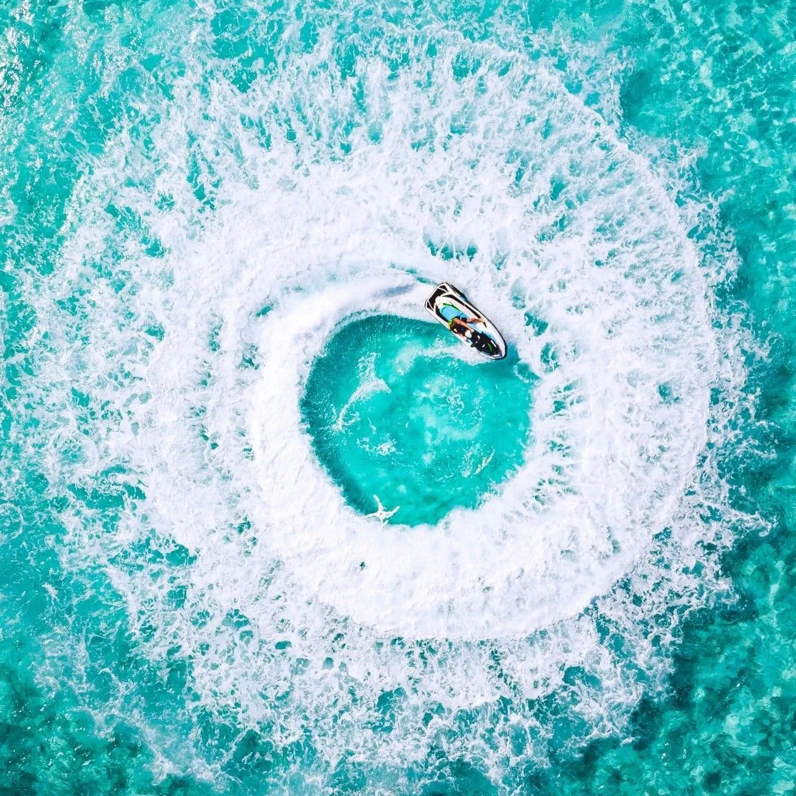 Vue aérienne d'une personne sur une motomarine dans une piscine ou un plan d'eau, créant un tourbillon autour d'elle.