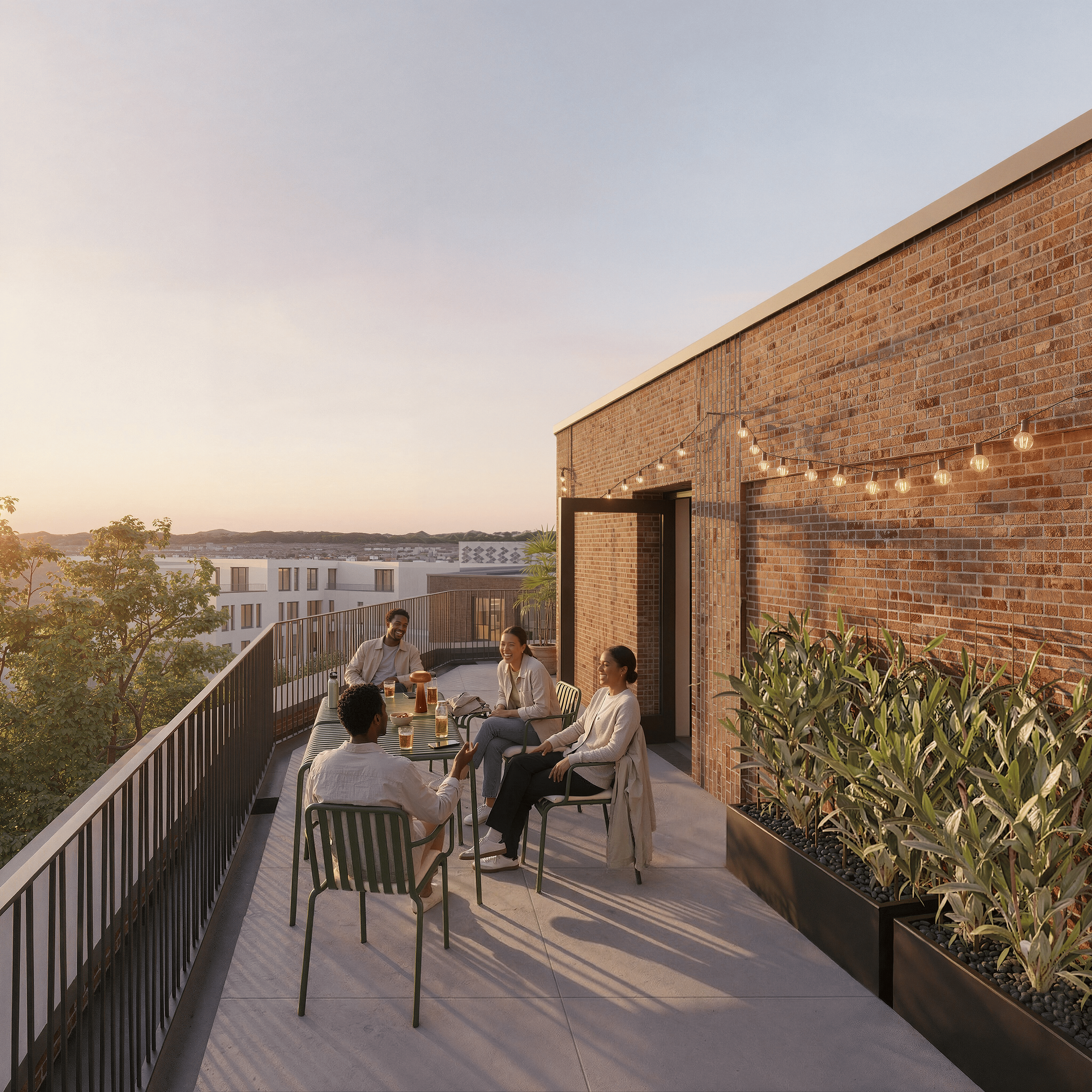 Menschen sitzen auf einer Dachterrasse mit Holztisch, Pflanzen und Lichterketten bei Sonnenuntergang, Blick auf Stadt und Berge im Hintergrund.