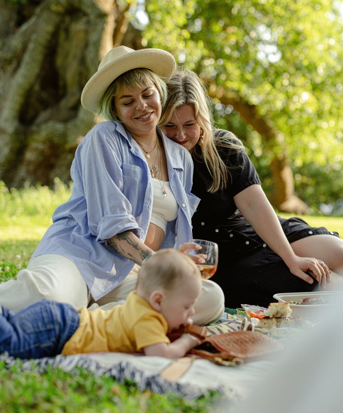 A femme couple having a picnic in the park with their baby