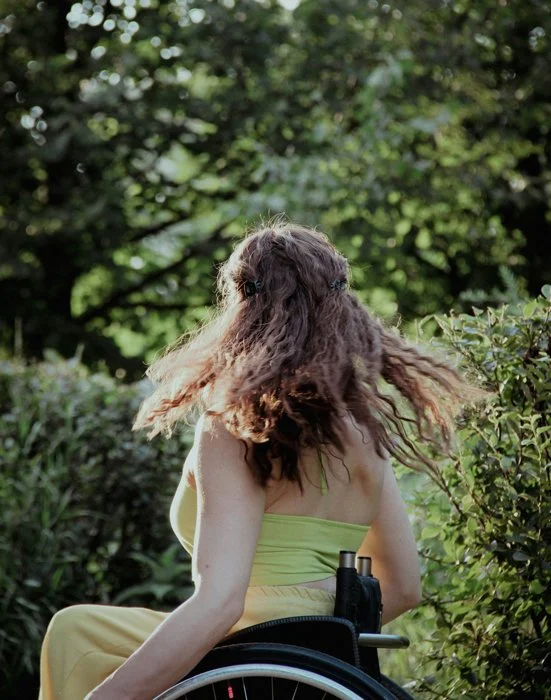 a woman in a wheelchair with her hair flowing through the air as if she's dancing