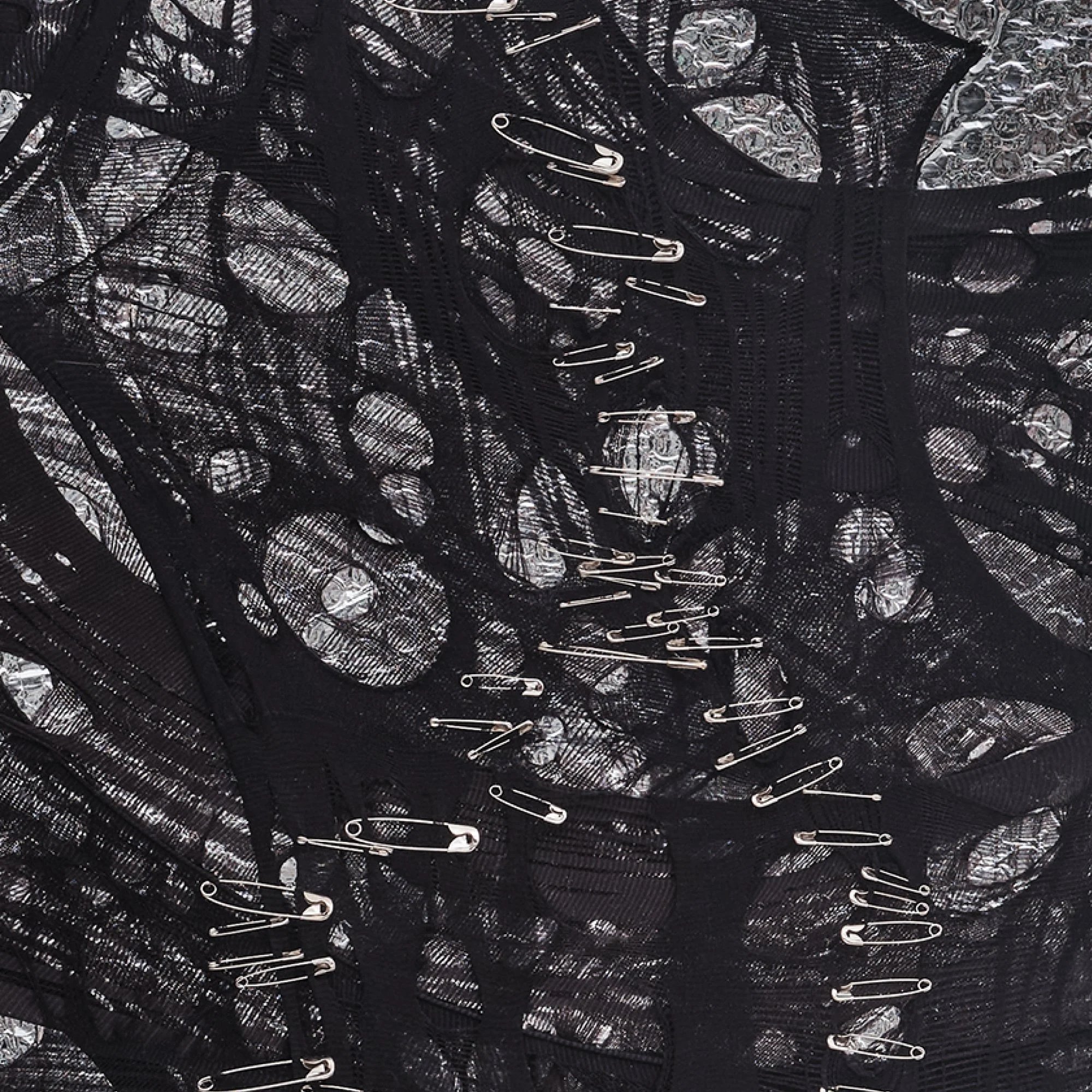 Textural detail of "Silver Dream" by Nicole Bajger; matte industrial fabric against light-reflective packaging.