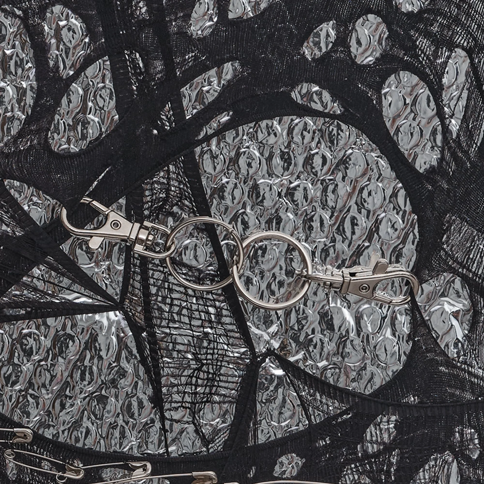 Macro view of "Silver Dreams: Act 2 - Infinity" by Nicole Bajger, showcasing the structural use of utilitarian metal bindings and the complex depth created by layered industrial materials.