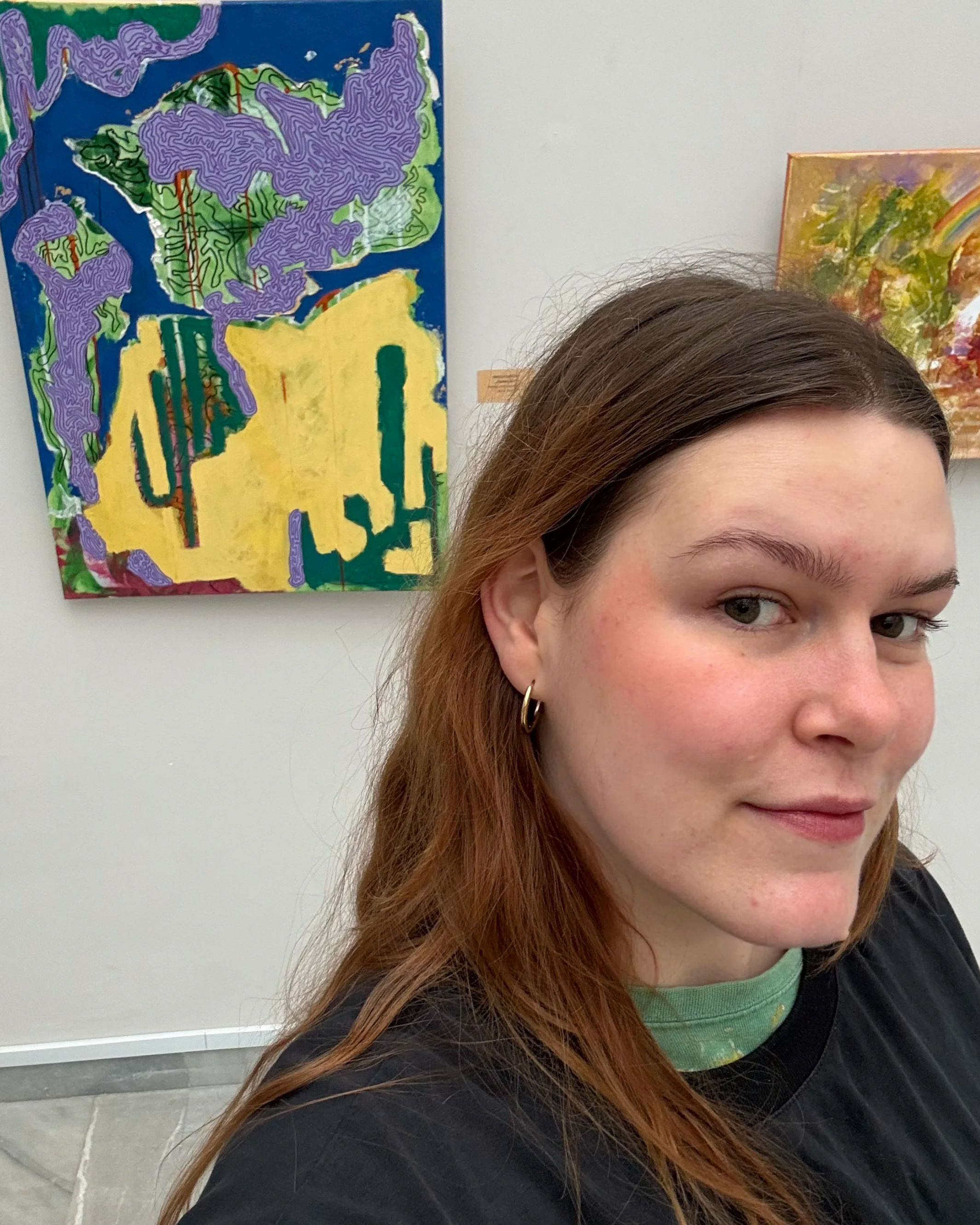 Portrait of contemporary artist Nicole Bajger at the Art Gallery "Vladimir Dimitrov-Maystora" during the Spring 2026 exhibition, standing in front of her original abstract paintings.