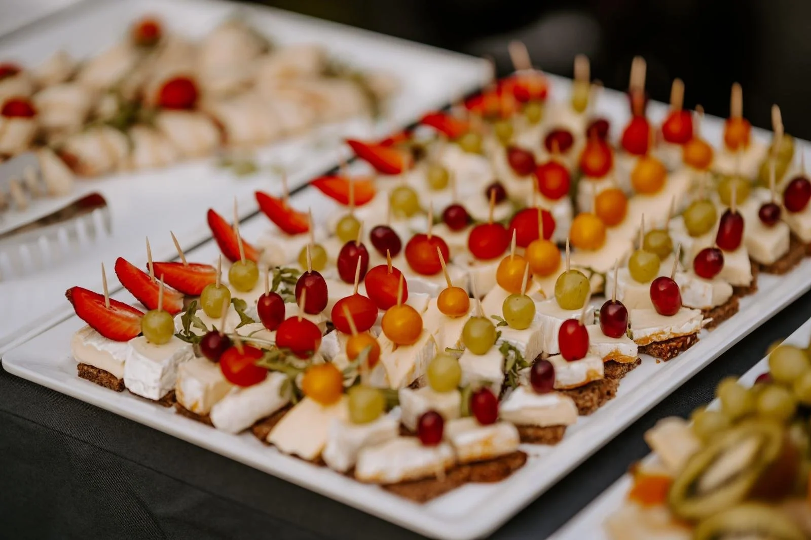 Bunte Canapés mit Früchten und Käse auf einem großen weißen Servierteller