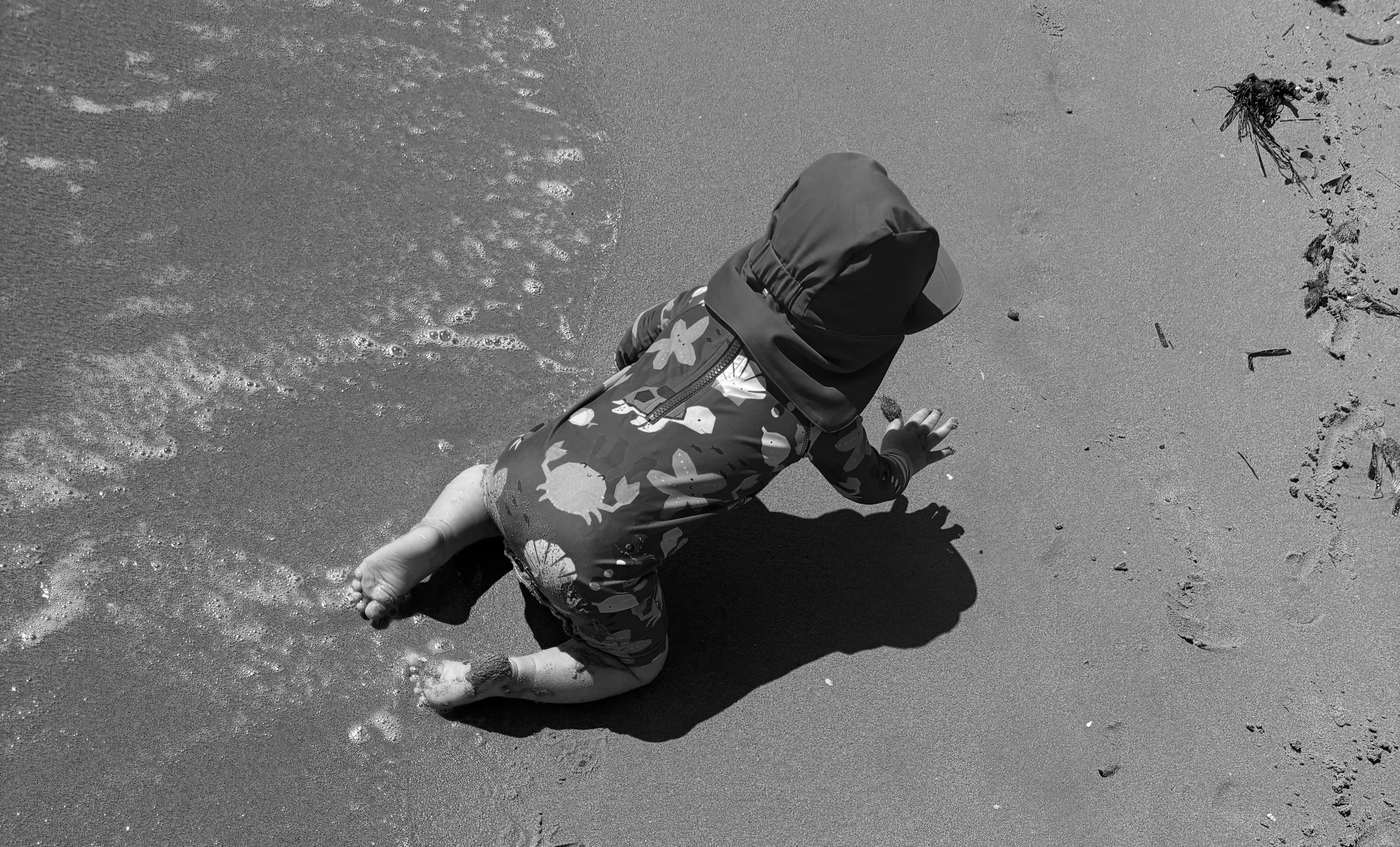Child crawling on a sandy beach viewed from above.